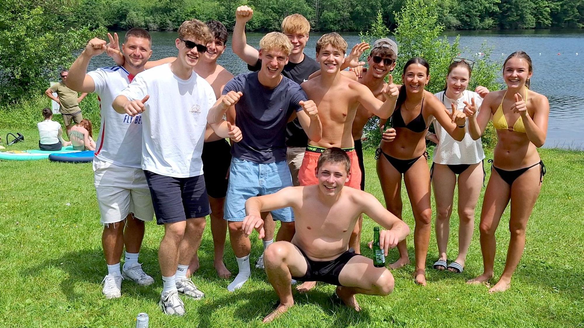 Eine Gruppe Jugendlicher posiert am Seeufer fürs Foto.