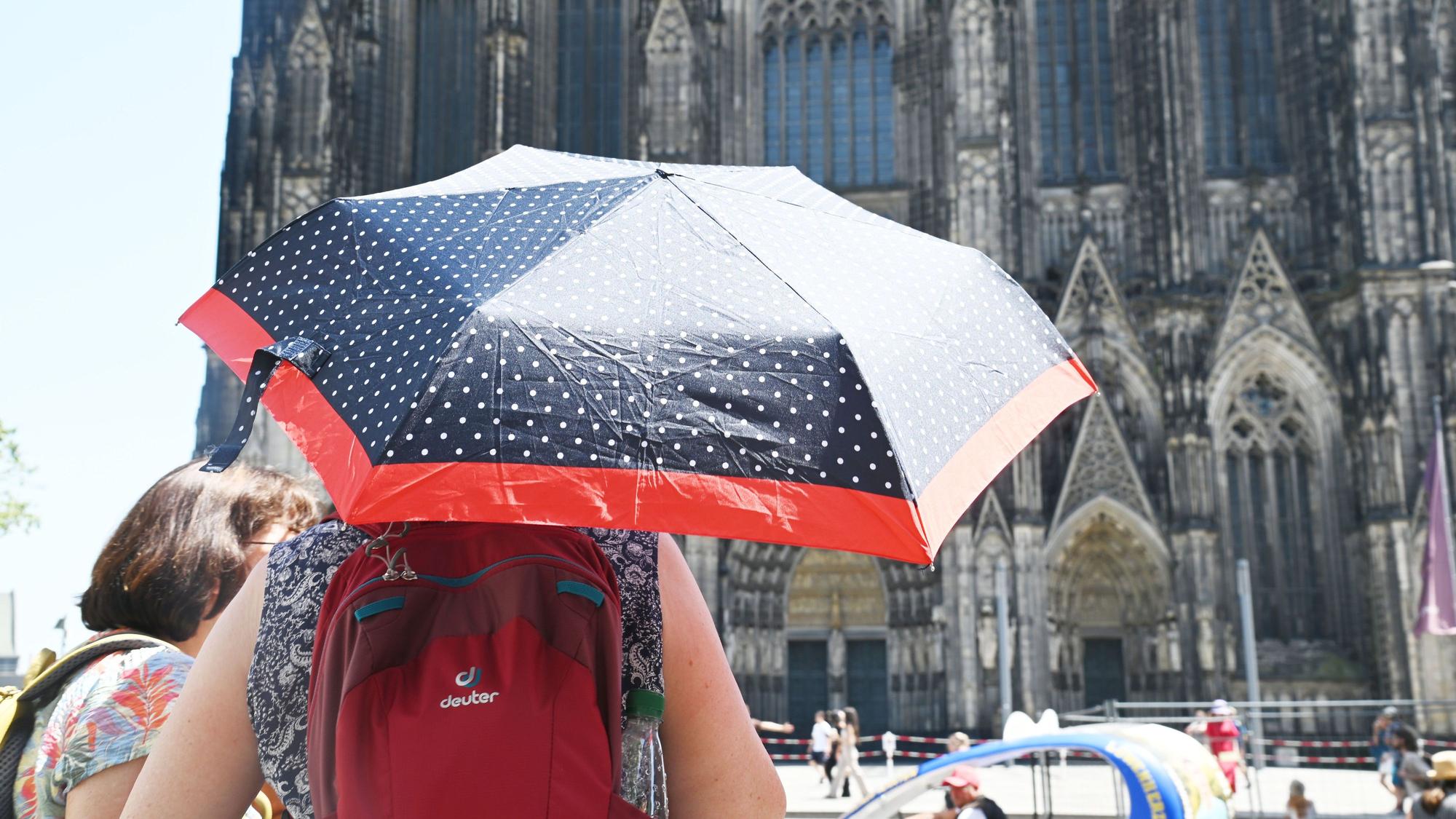 Eine Person schützt sich mit einem Schirm vor der Sonne.