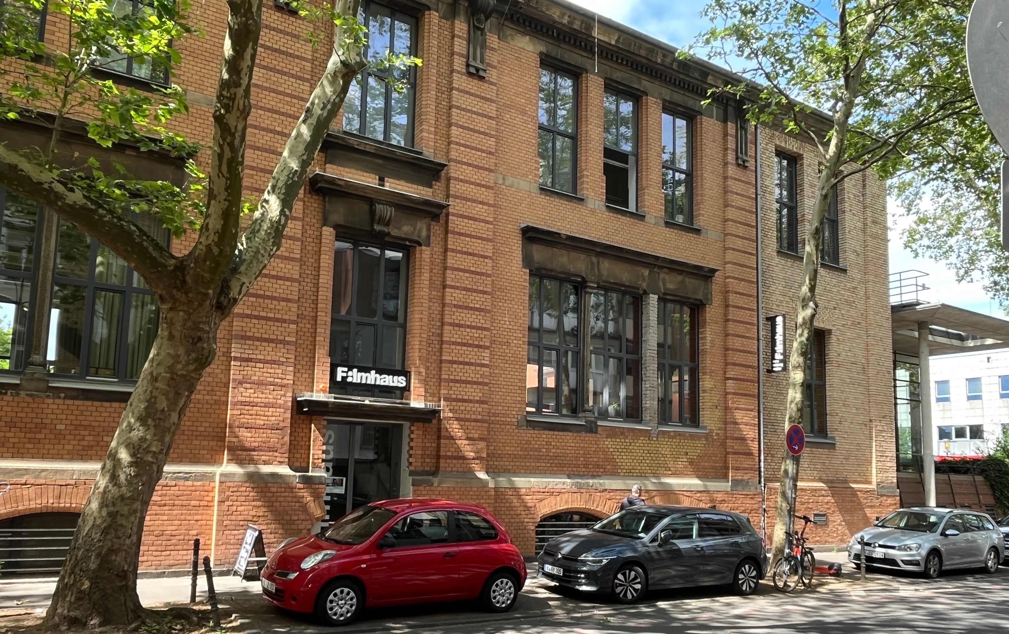 Ein Backsteingebäude mit dem Schriftzug „Filmhaus“ über dem Eingang steht an einer Straße.