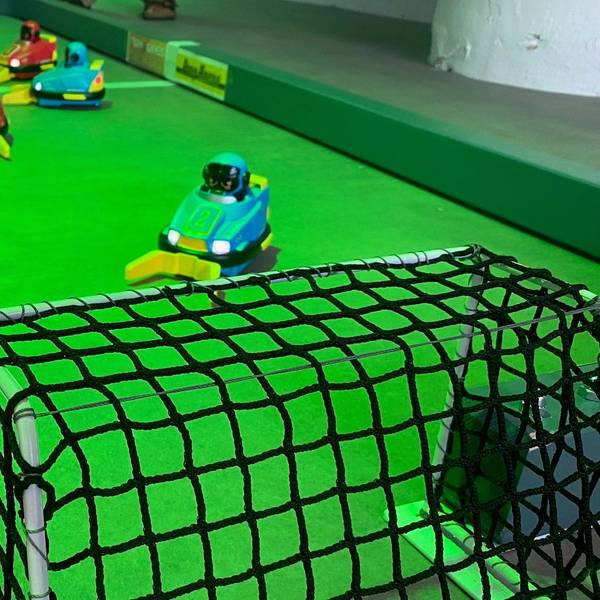 Zu sehen ist ein Miniatur-Fußballfeld mit ferngesteuerten Autos.