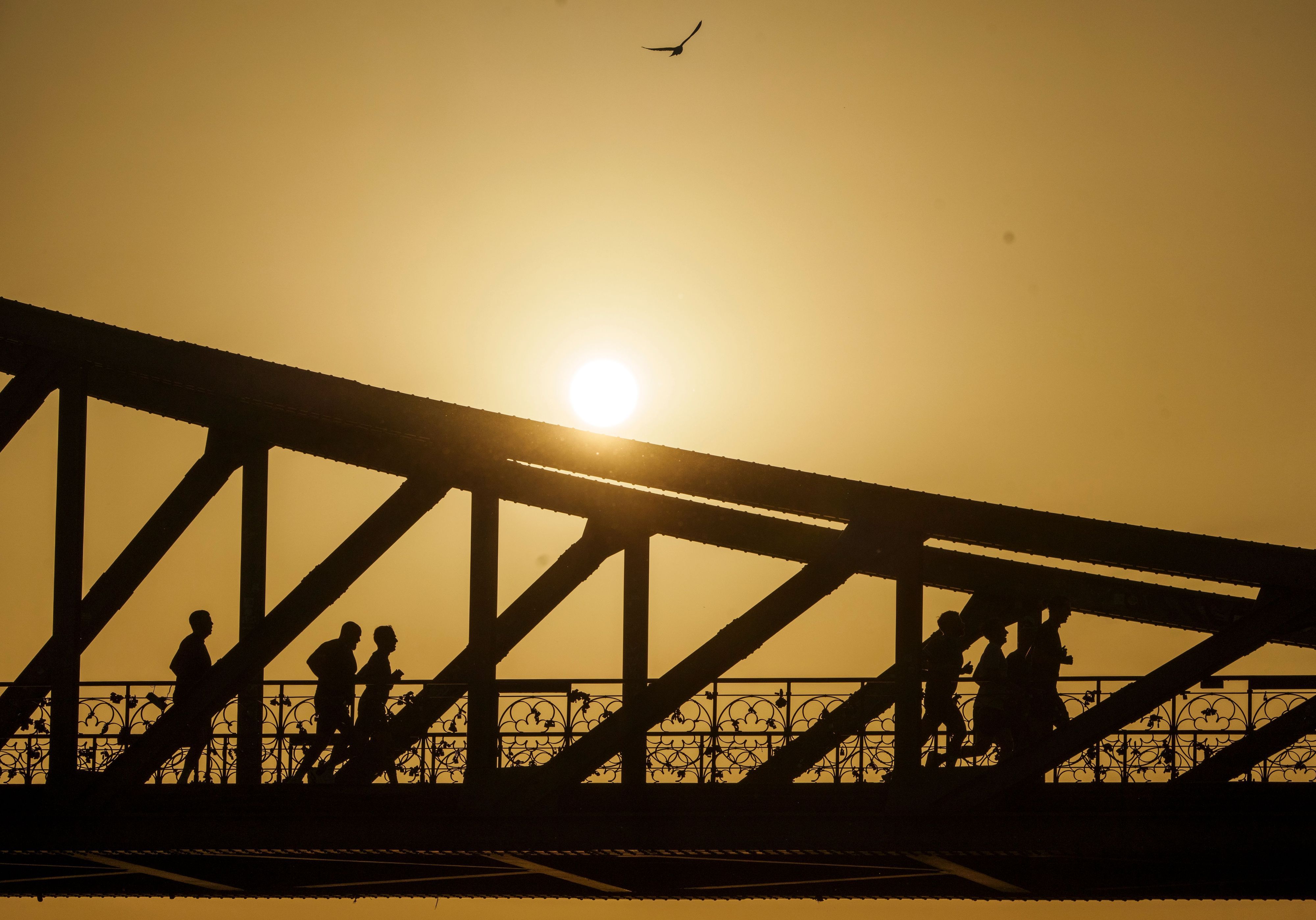 Eine Gruppe joggt bei Sonnenaufgang über den Eisernen Steg in Frankfurt am Main.