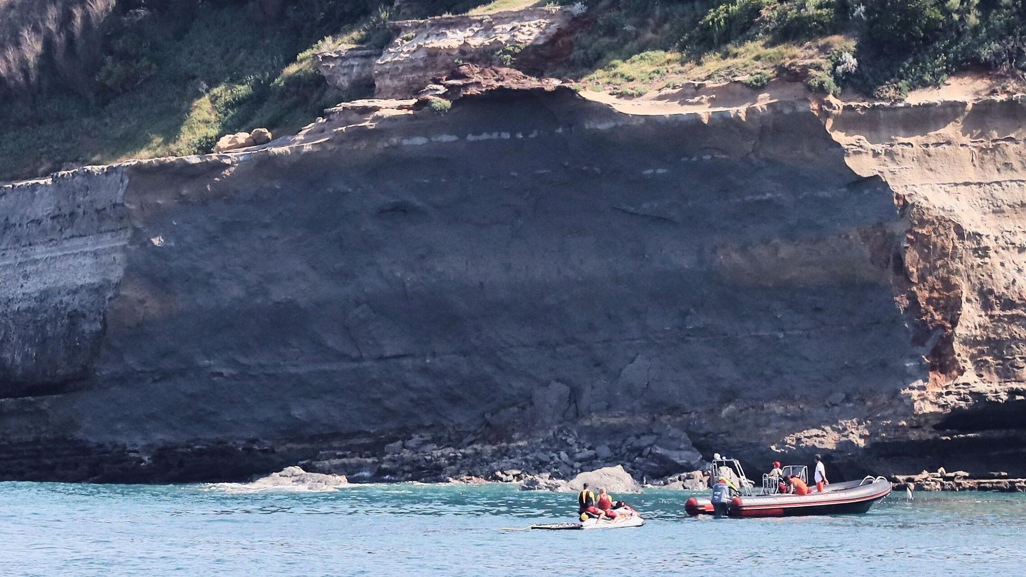 Rettungskräfte suchen von Booten aus nach einer vermissten Person in der Nähe eines riesigen Küstenabschnitts. Am Mittwochabend ist ein großer Felsen von einer Steilküste abgebrochen und ins Meer gestürzt, wobei ein Taucher ums Leben kam und ein weiterer vermisst wird.