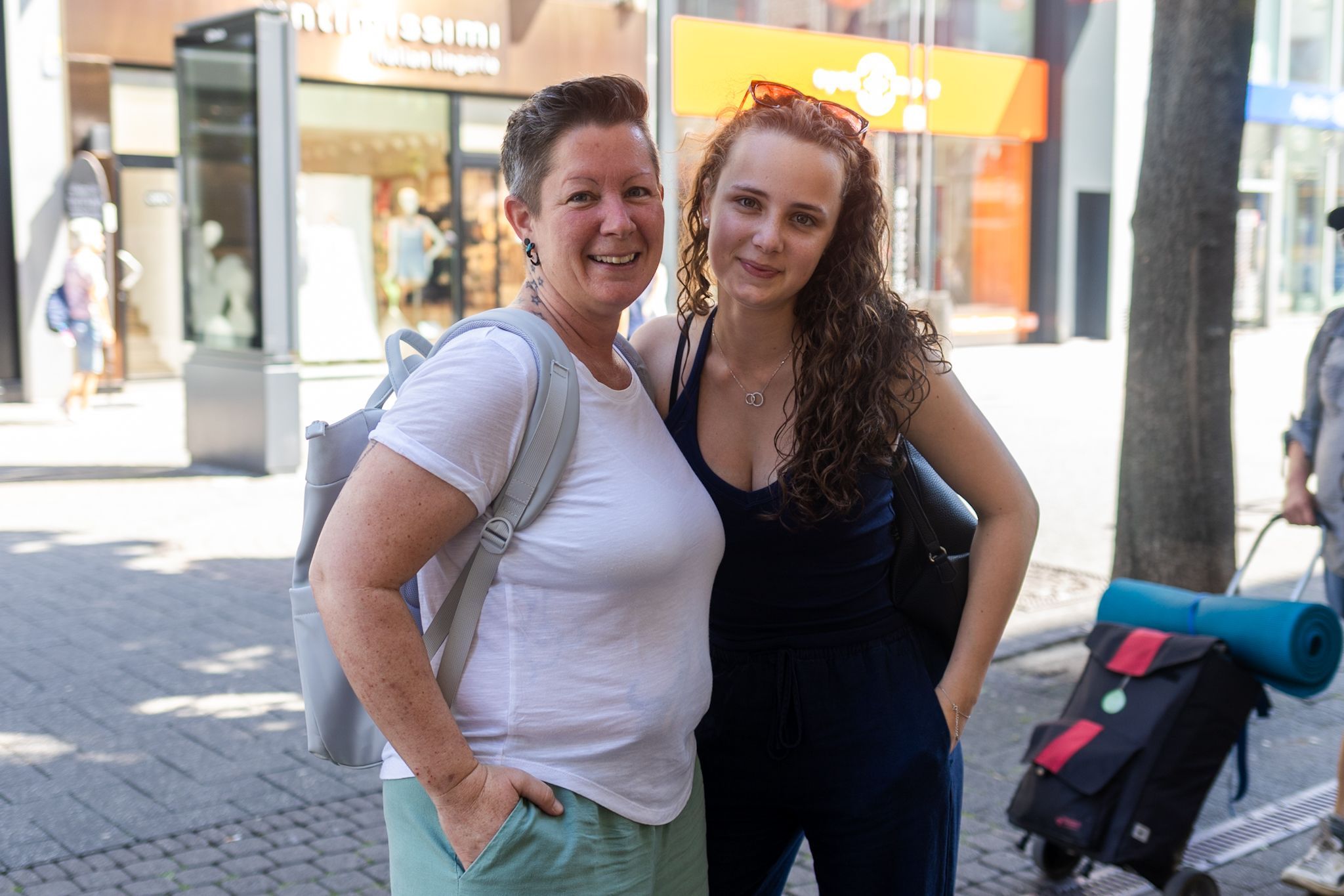 Mutter und Tochter lächeln Arm in Arm in die Kamera.