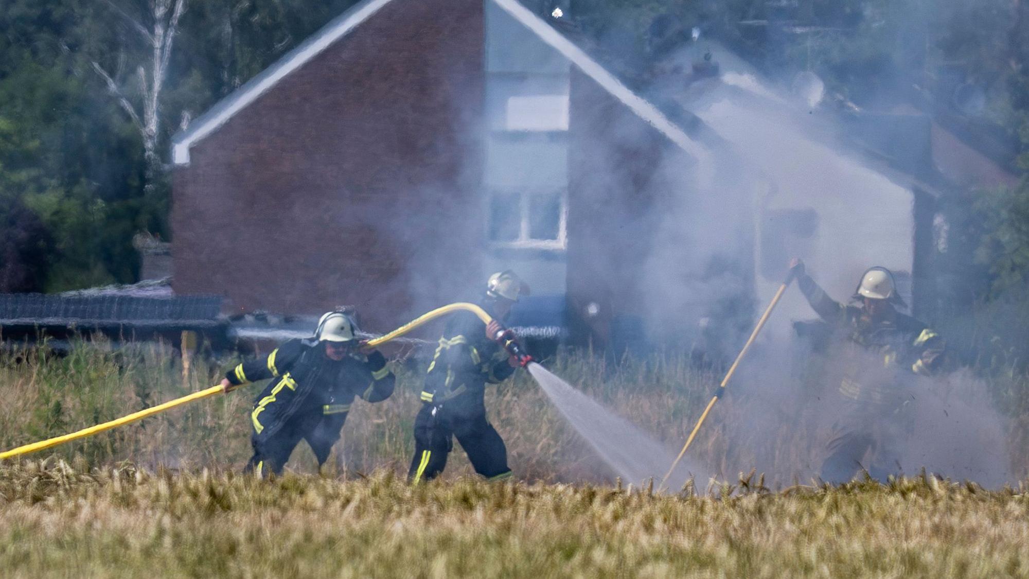 Feuerwehrkräfte löschen einen Brand auf einem Feld.