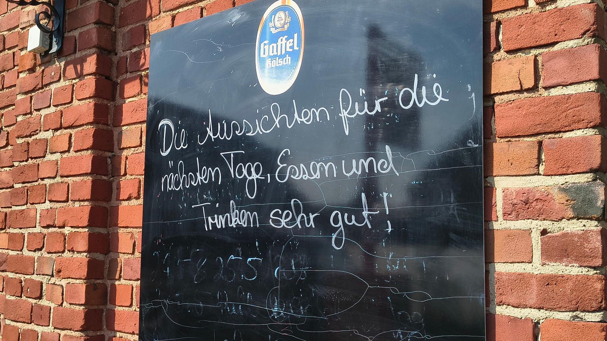 Auf einer Tafel an einer Gaststätte in Köln-Merkenich in Langel steht: „Die Aussichten für die nächsten Tage, Essen und Trinken sehr gut!“