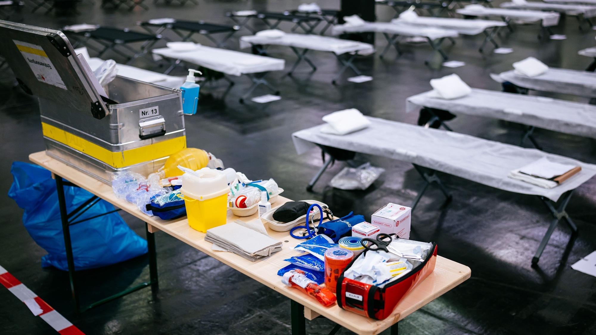 Feldbetten und medizinisches Material stehen im Notfallversorgungszentrum der Feuerwehr Köln in einer gekühlten Messehalle bereit.