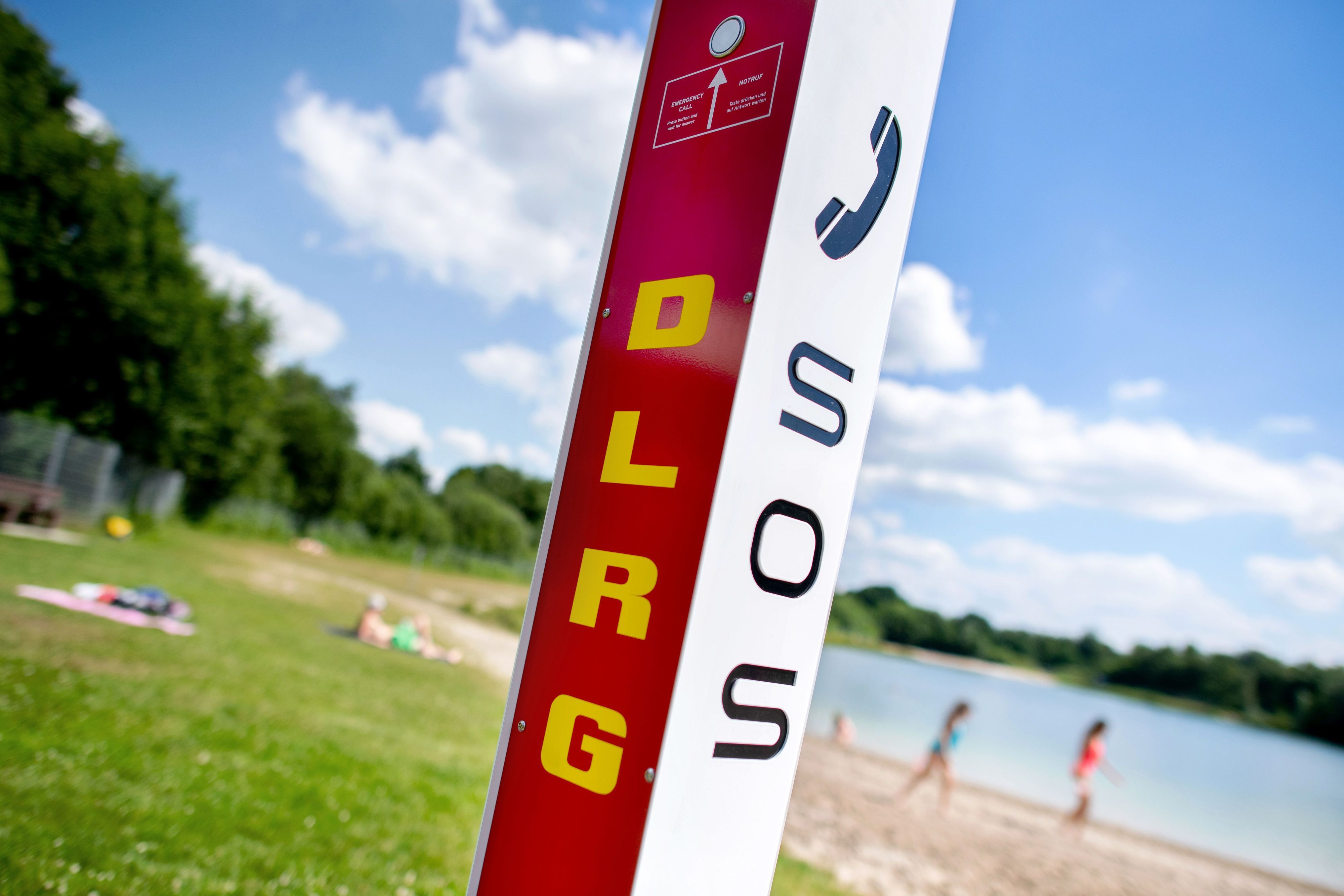 Eine Notrufsäule der DLRG steht an einem Badesee.
