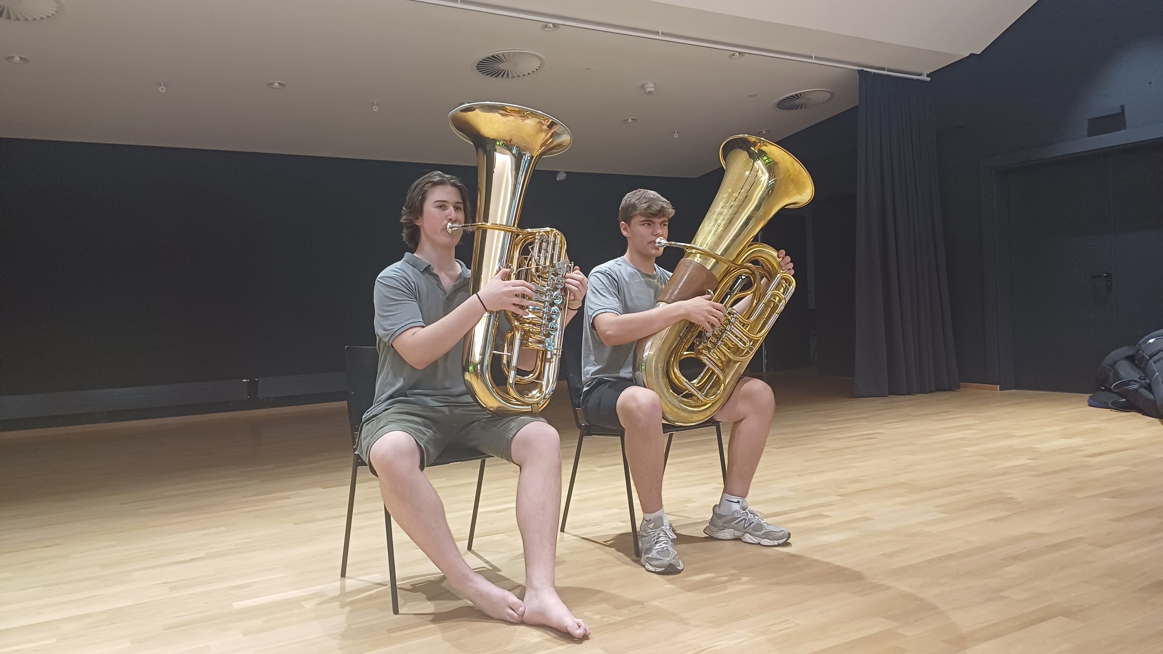 Zwei Tubisten proben in einem Saal.