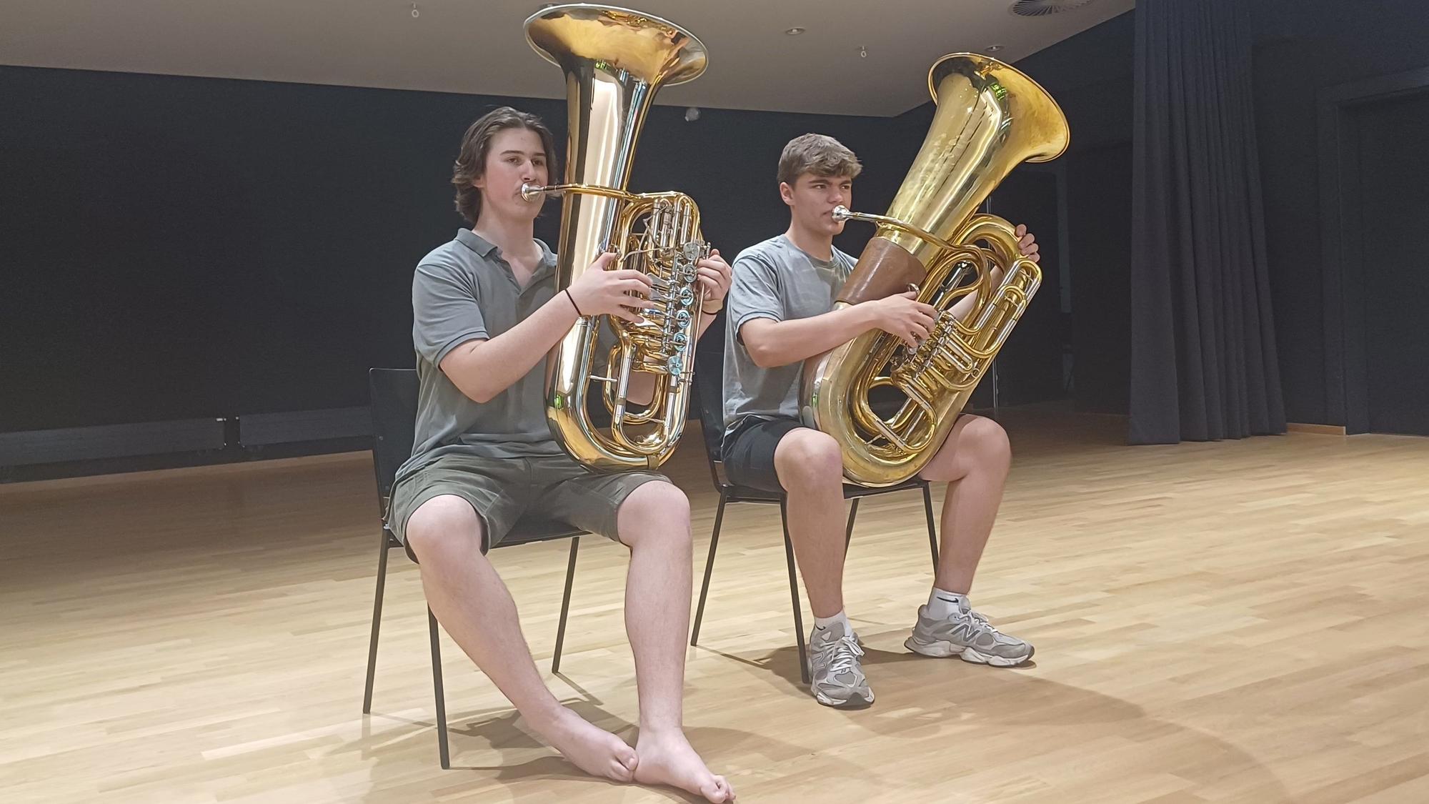 Zwei Tubisten proben in einem Saal.