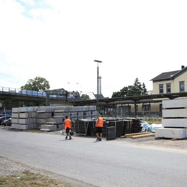 Bauteile auf einer Betonfläche im Hintergrund ein Bahnhof.