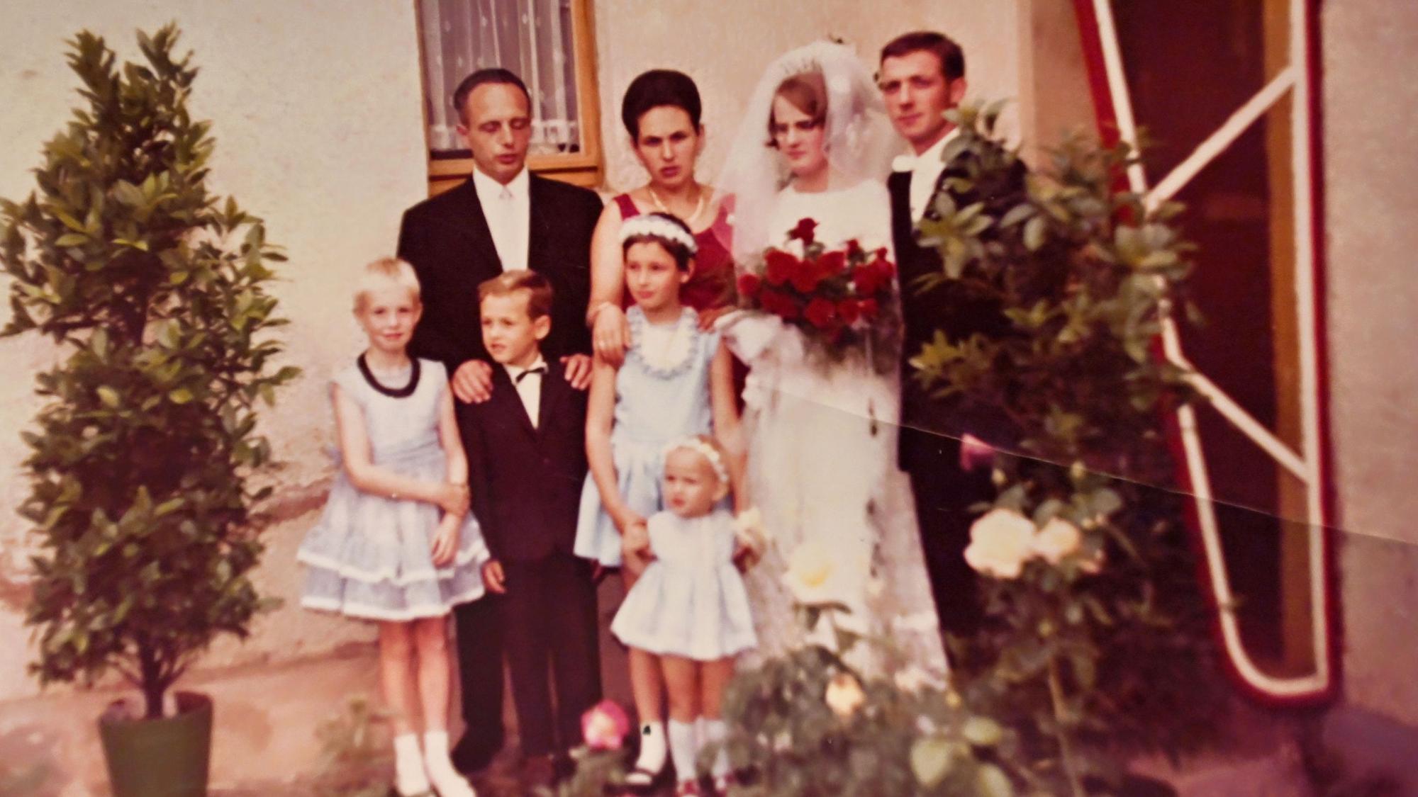 Das Fotos aus dem Jahr 1964 zeigt ein Hochzeitspaar mit einigen Gästen.