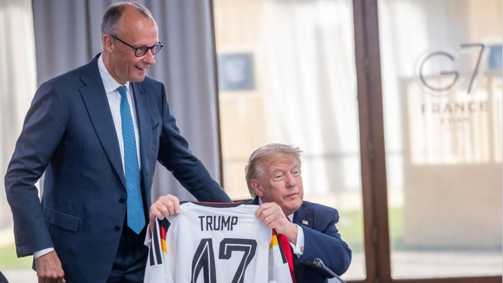 Vor zwei Wochen schenkte Bundeskanzler Friedrich Merz (l, CDU) ein DFB Fußball-Trikot an US-Präsident Donald Trump mit der Rückennummer 47. Für seinen Post zum Aus der DFB-Elf bei derm WM erntete Merz Unverständnis.