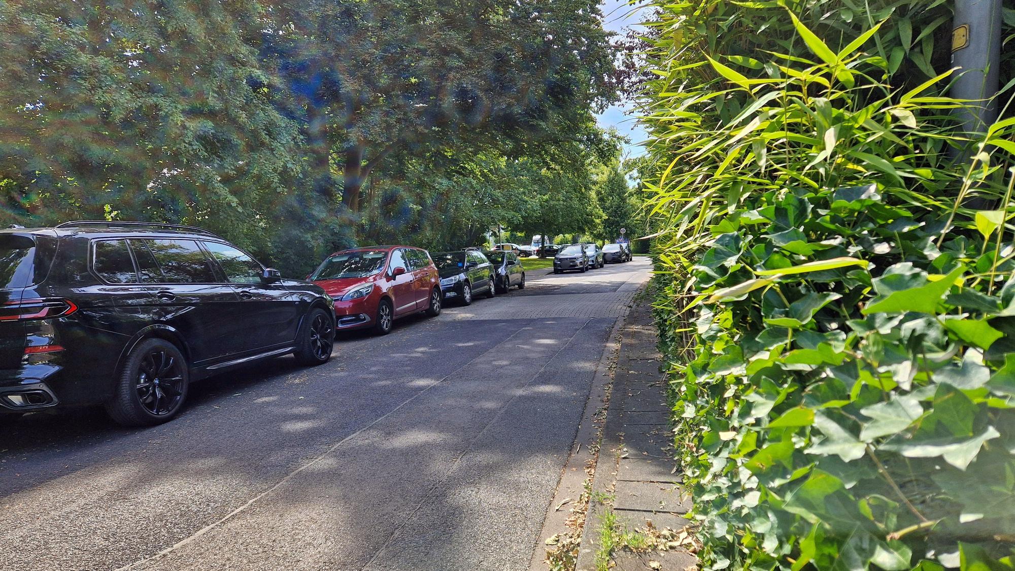 An einer sehr schmalen Straße stehen abgestellte Autos.