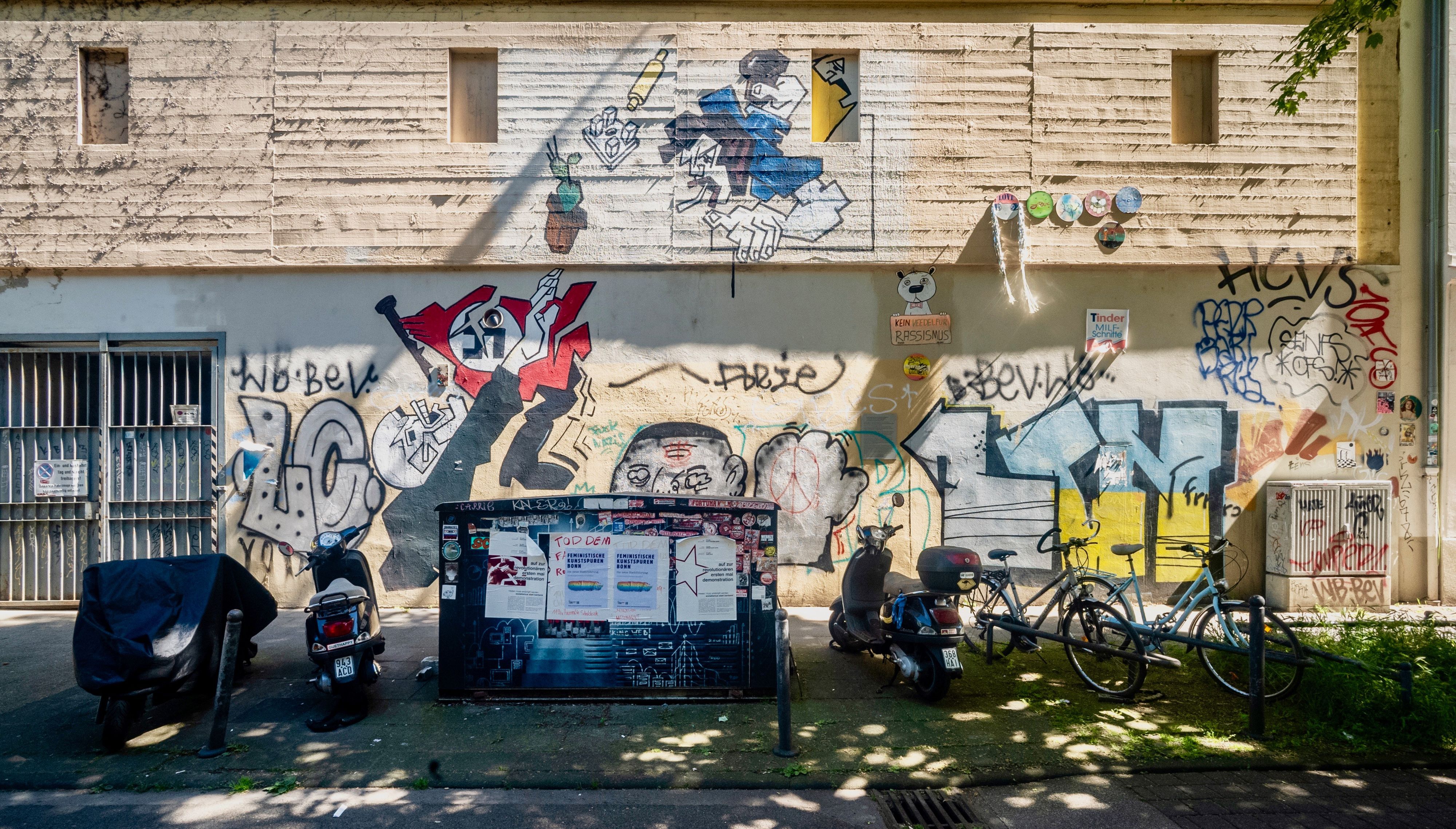 Auf einer Hauswand sind zahlreiche Wandbilder, aber auch lieblose Farbschmierereien hinterlassen worden.