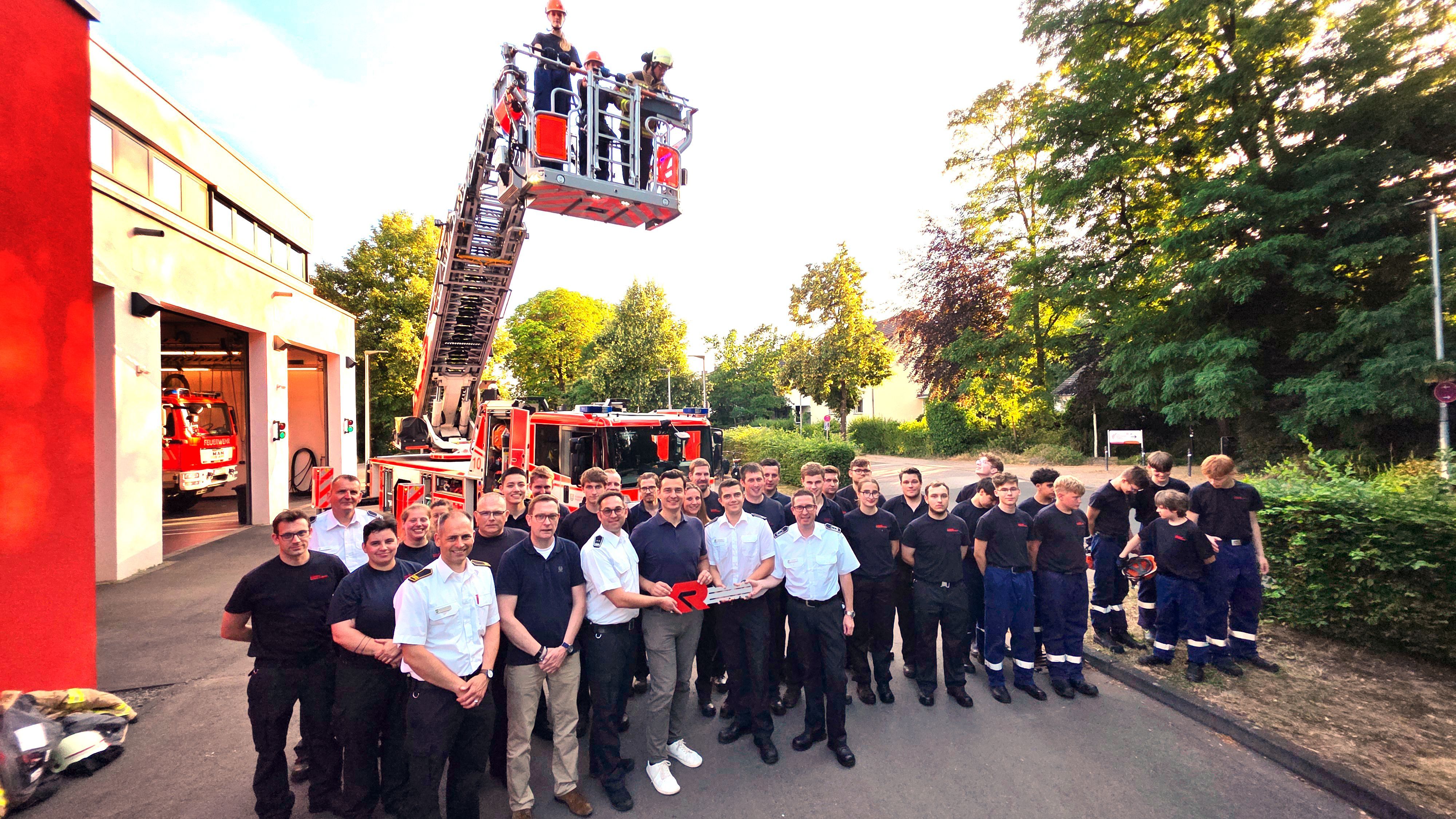 Feuerwehrleute und Vertreter der Stadt Bergisch Gladbach stehen vor der neu in Dienst gestellten Drehleiter in Bergisch Gladbach-Refrath.