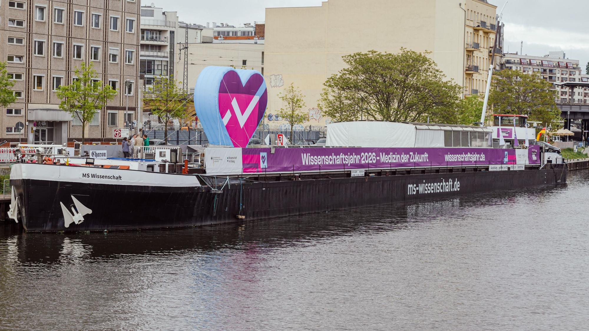 Ein großes Schiff auf dem Wasser liegt am Hafen, im Hintergrund Häuser.