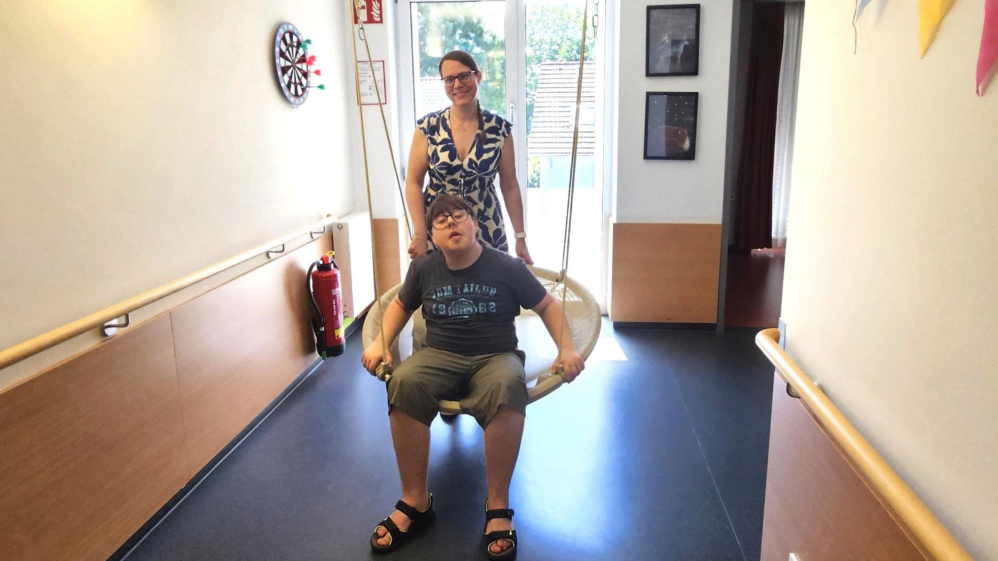 Das Foto zeigt Jonas in einem Schaukelnest, dahinter seine Mutter Nicole Fuchs.
