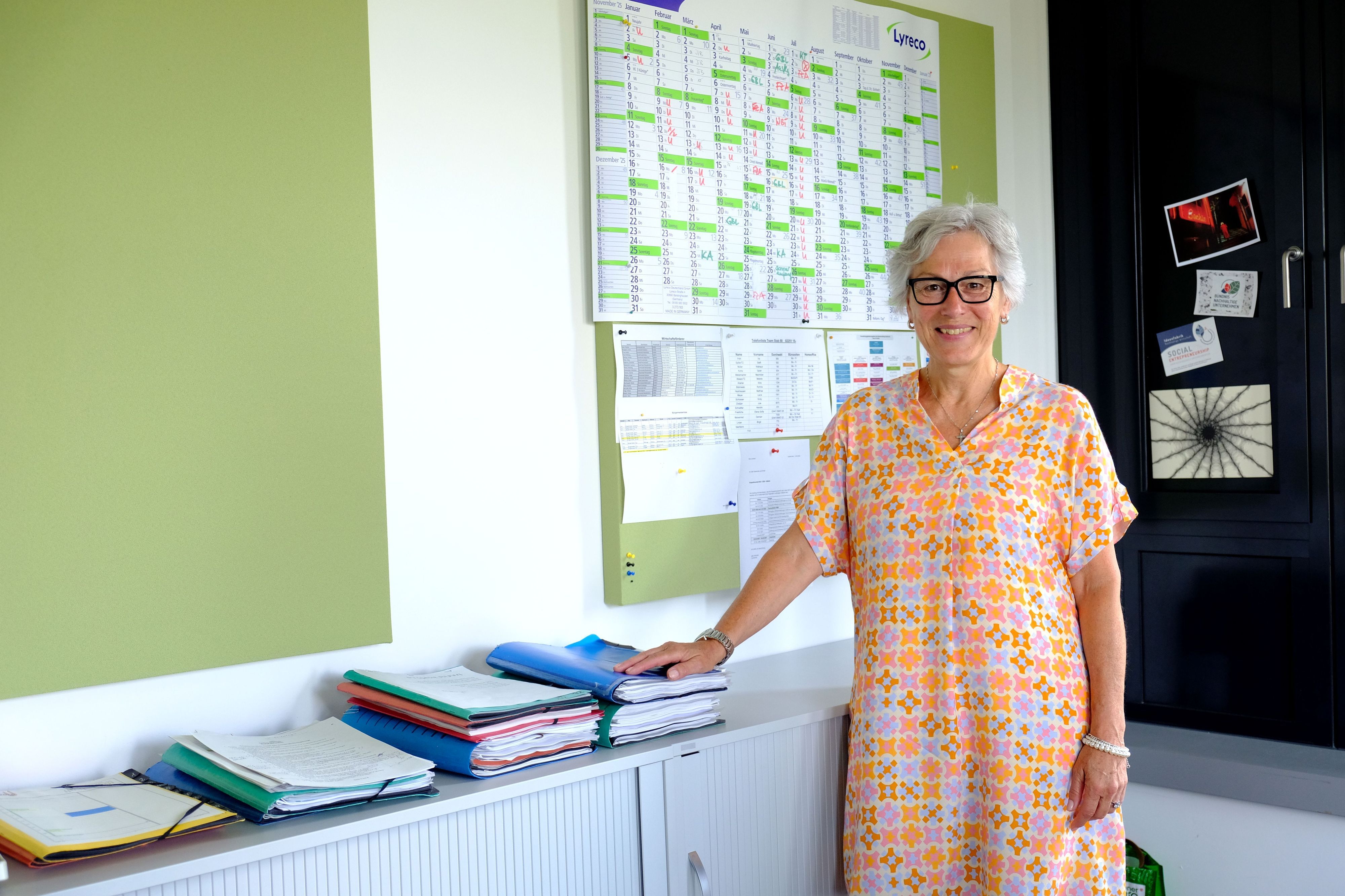 Iris Poth mit einem orange-gemusterten Sommerkleid in ihrem Büro in der Euskirchener Kreisverwaltung.