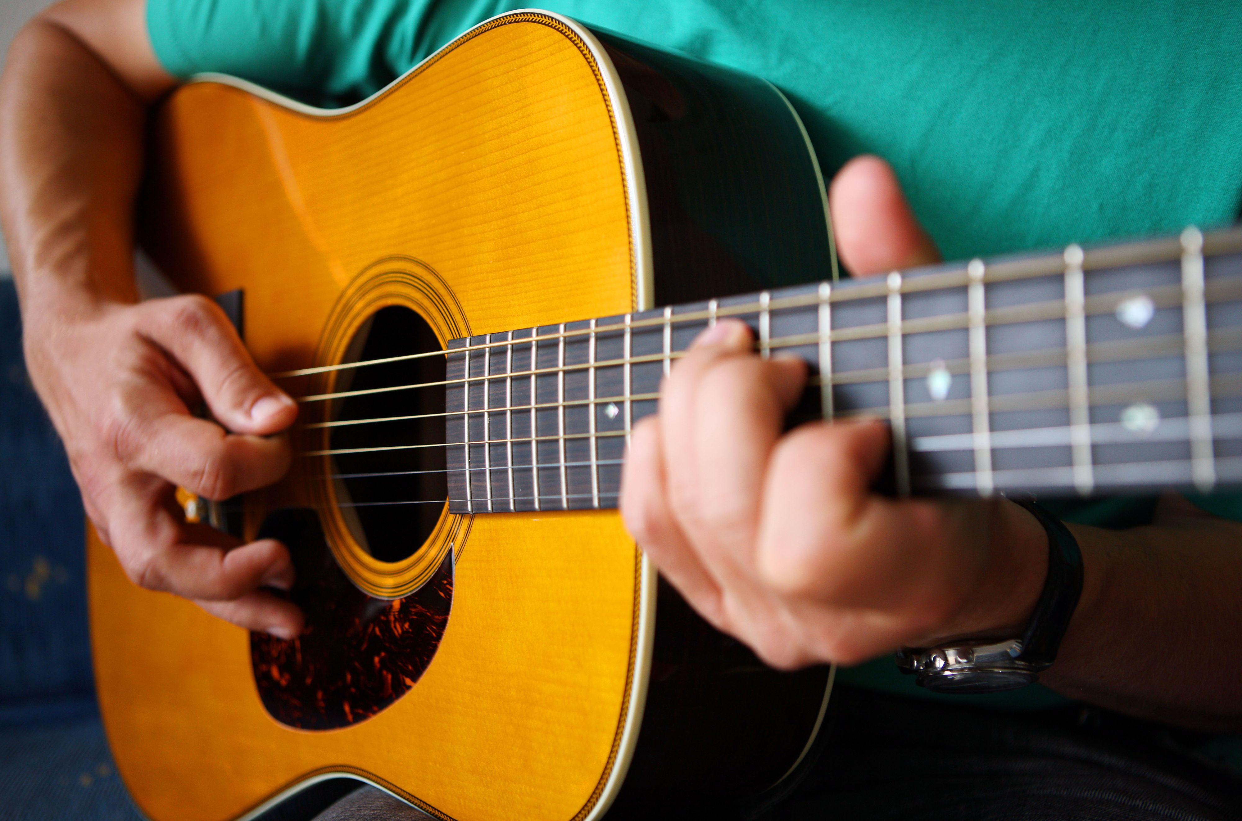 Ein Gitarrist spielt auf einer Stahlsaiten Dreadnought Akustikgitarre.