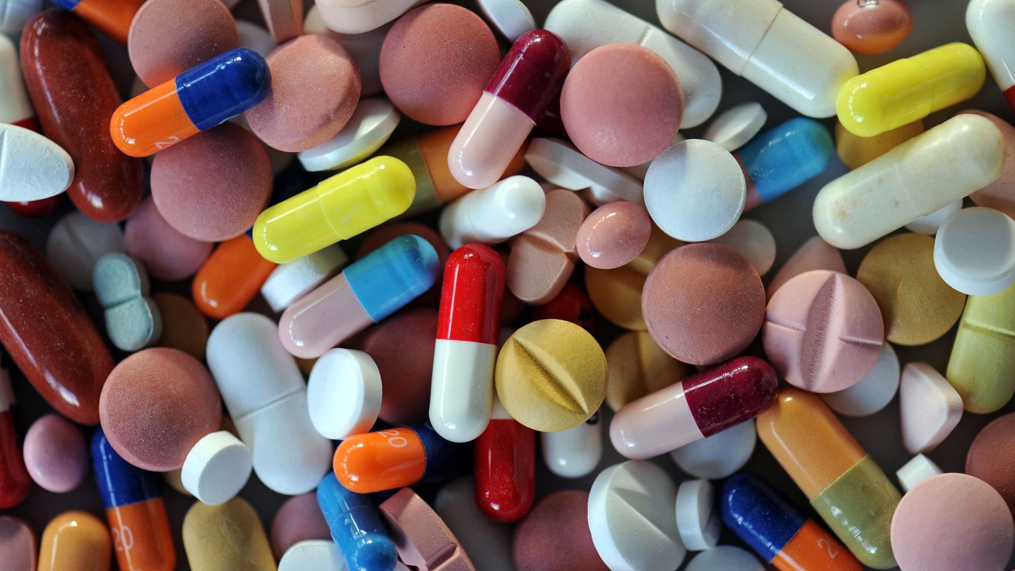 Verschiedene Pillen und Tabletten liegen auf einem Teller.