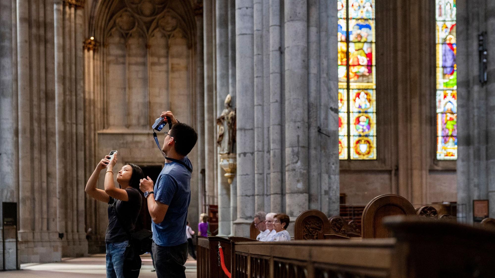 Touristen fotografieren während einer Besichtigung im Kölner Dom.