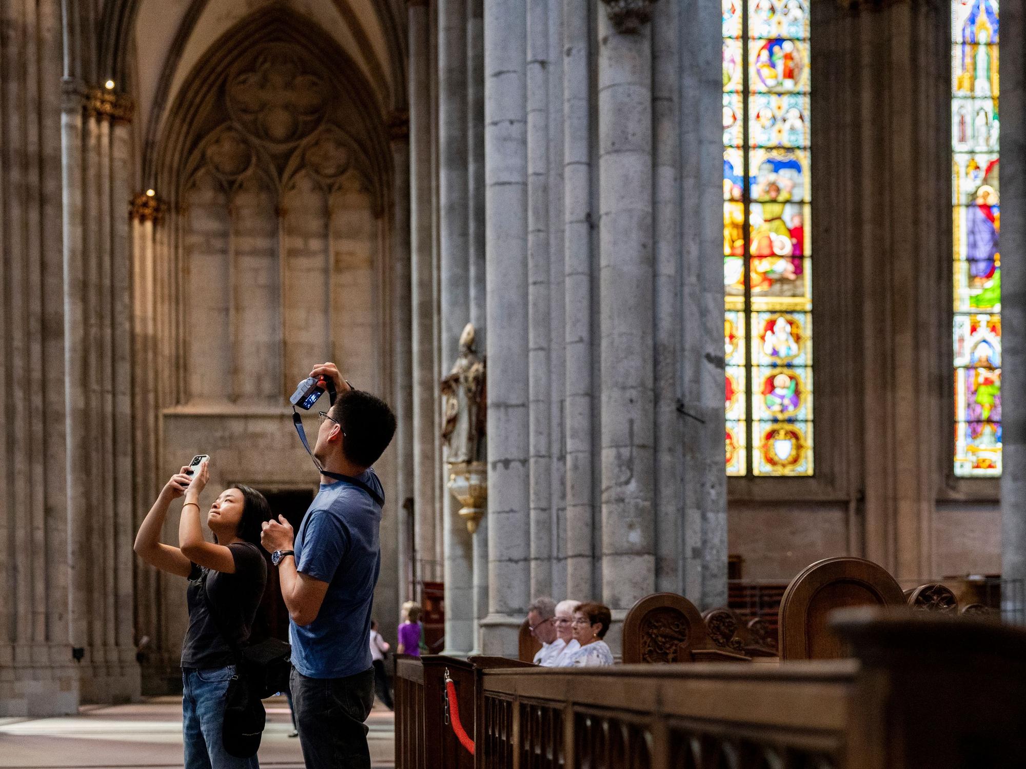 Ein Touristen-Paar macht im Kölner Dom Fotos.