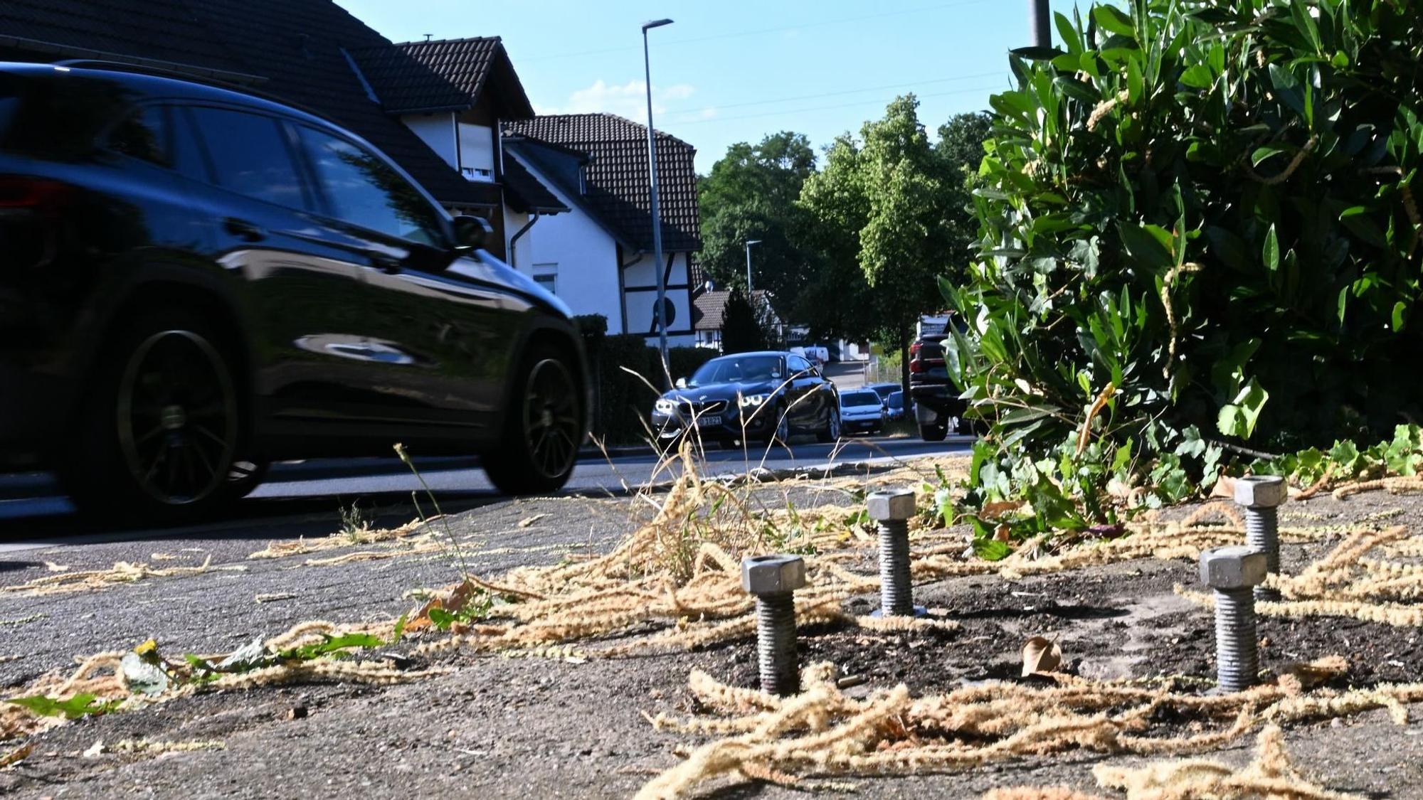Vier dicke Schrauben im Boden neben einer Straße.