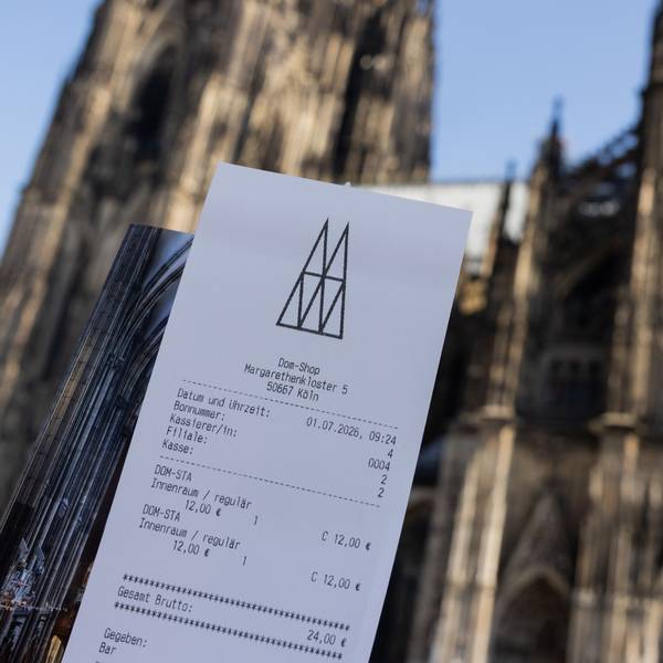 Eine Touristin zeigt ihr Ticket vor dem Kölner Dom. Der Eintritt in den Kölner Dom kostet ab dem 1. Juli zwölf Euro für Besucher. Betende sollen in einen bestimmten Bereich weiterhin kostenlos Zutritt erhalten. +++ dpa-Bildfunk +++