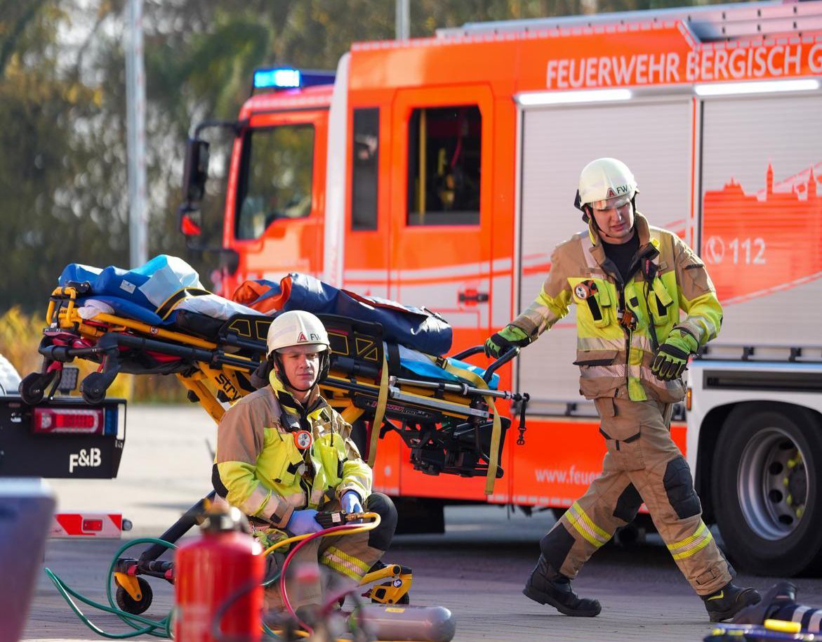 Ein Feuerwehrmann fährt eine Rettungstrage vor einem Löschfahrzeug vorbei.
