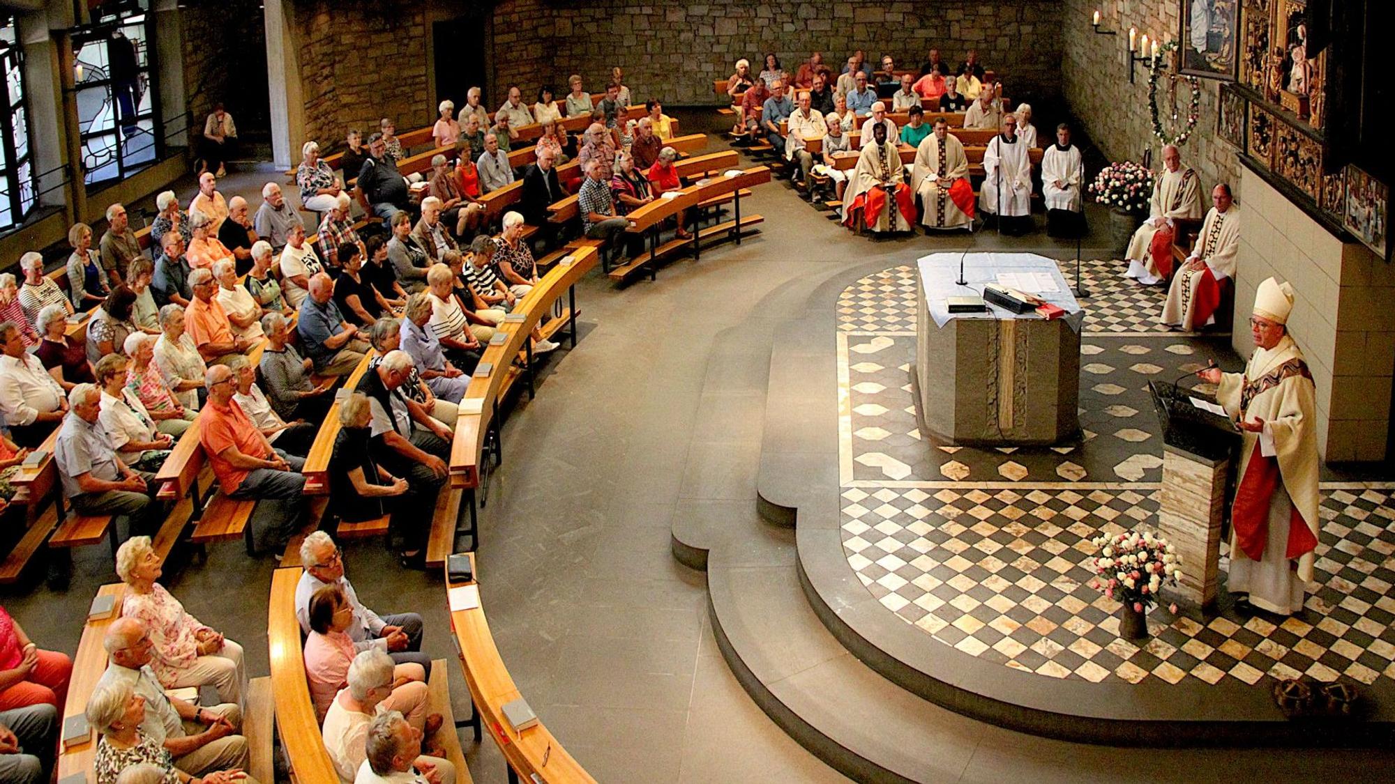 Das Bild zeigt den vollbesetzten Kirchenraum von oben, der Bischof steht am Ambo und spricht.