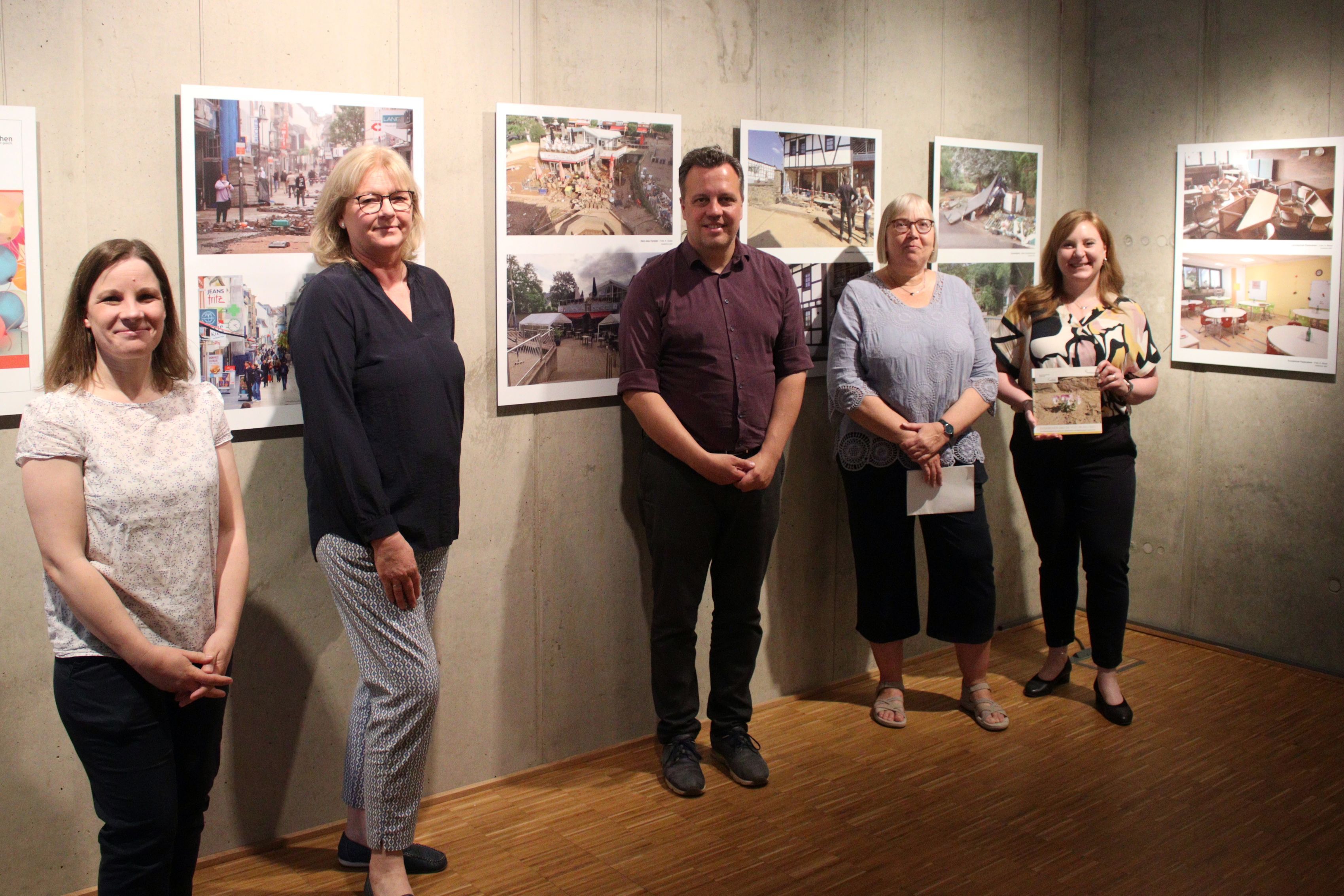 Maja Kützemeier (v.l., Ausstellungskuratorin), Dr. Heike Lützenkirchen (Leiterin Stadtmuseum), Sacha Reichelt (Bürgermeister), Silke Winter (Abteilungsleiterin bei der Stadt) und Sabine Dünnwald (Leitern Stadtarchiv) stehen vor den Bildern der Ausstellung.