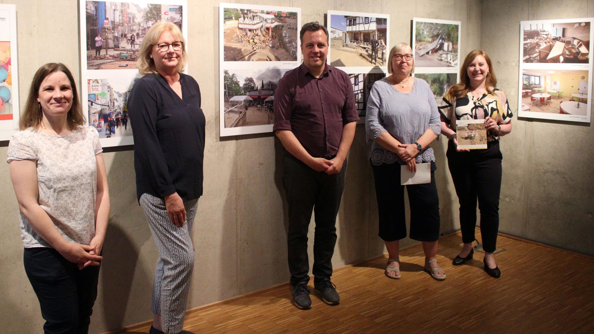 Maja Kützemeier (v.l., Ausstellungskuratorin), Dr. Heike Lützenkirchen (Leiterin Stadtmuseum), Sacha Reichelt (Bürgermeister), Silke Winter (Abteilungsleiterin bei der Stadt) und Sabine Dünnwald (Leitern Stadtarchiv) stehen vor den Bildern der Ausstellung.