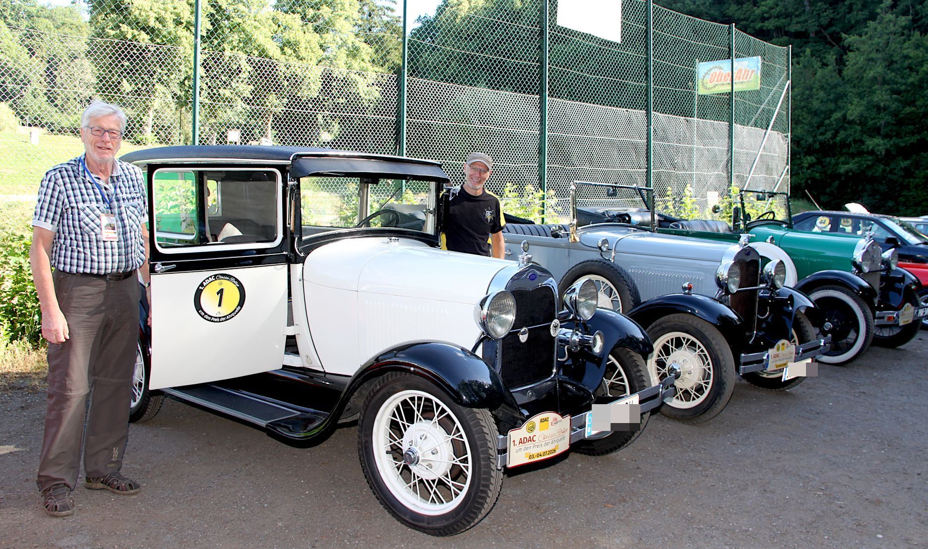 Zwei Männer stehen neben einer Reihe von Oldtimern.