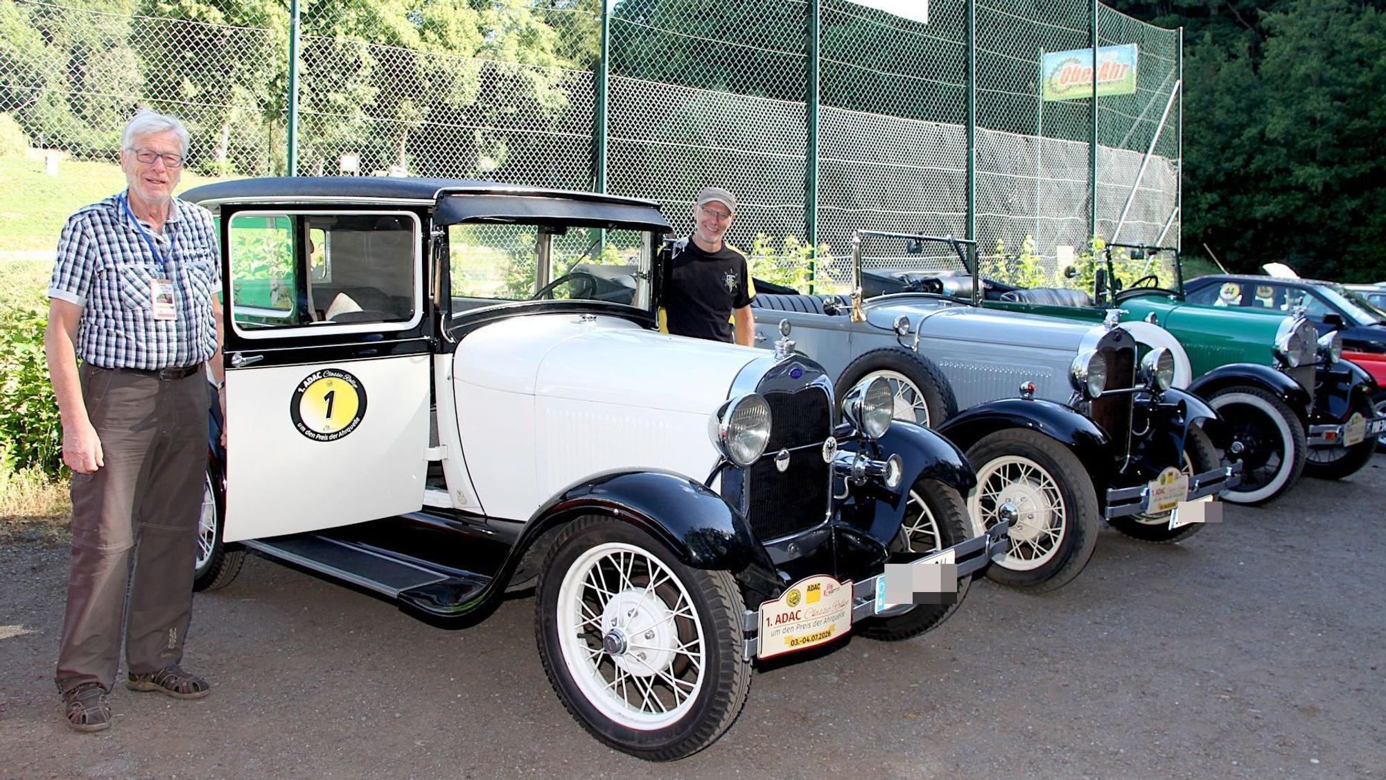 Zwei Männer stehen neben einer Reihe von Oldtimern.
