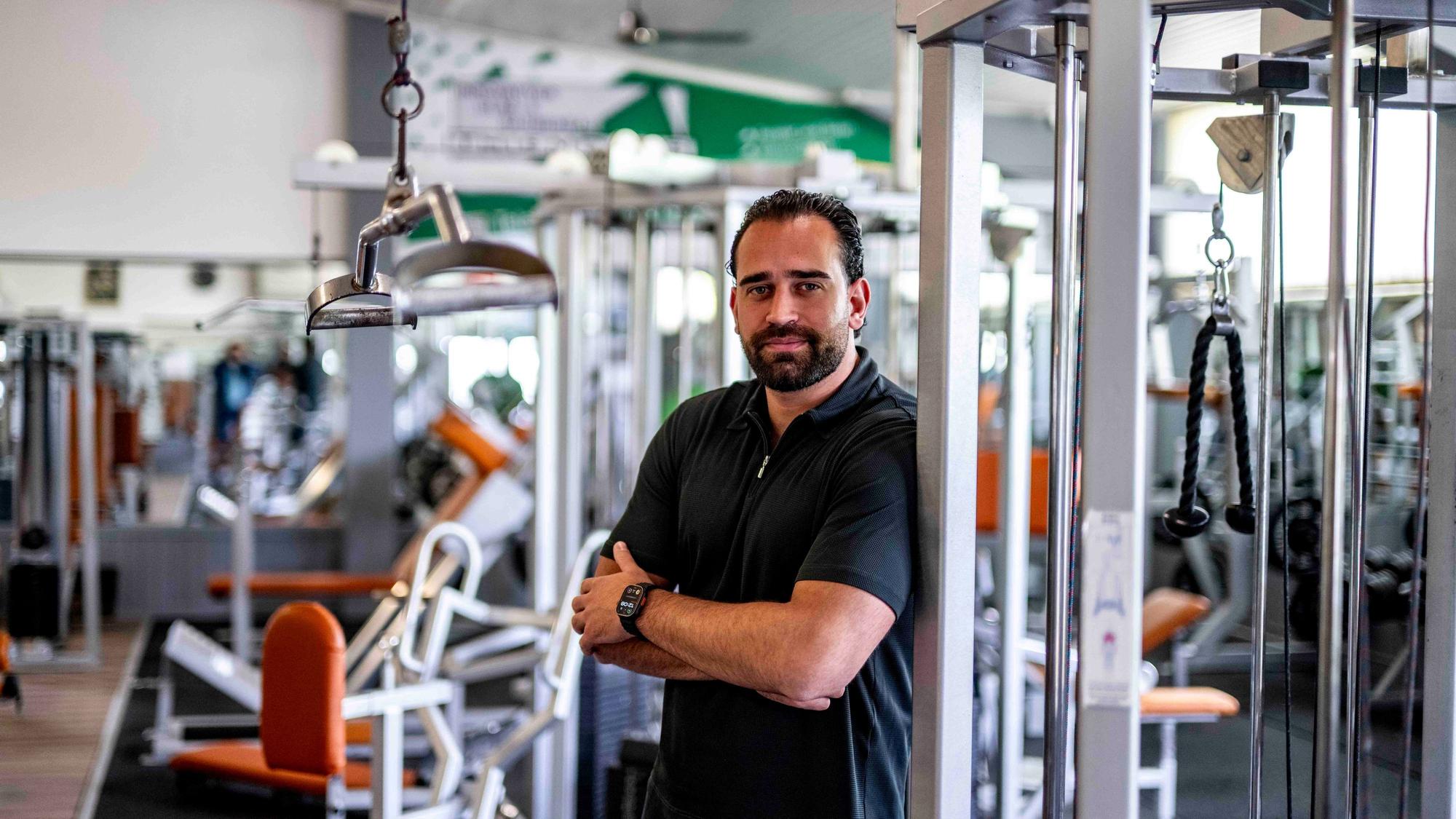 Zeller steht vor einem der Fitnessgeräte, er hat die Arme verschränkt.