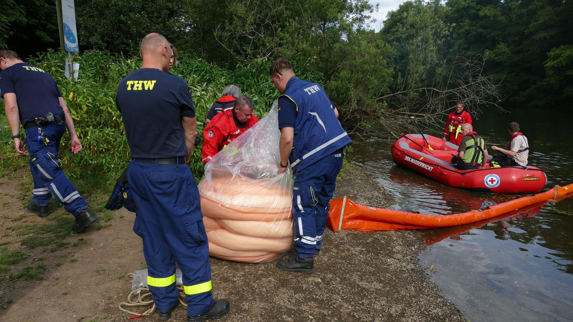 Mit einem Boot bringen die Einsatzkräfte Saugkörper auf der Sieg aus.