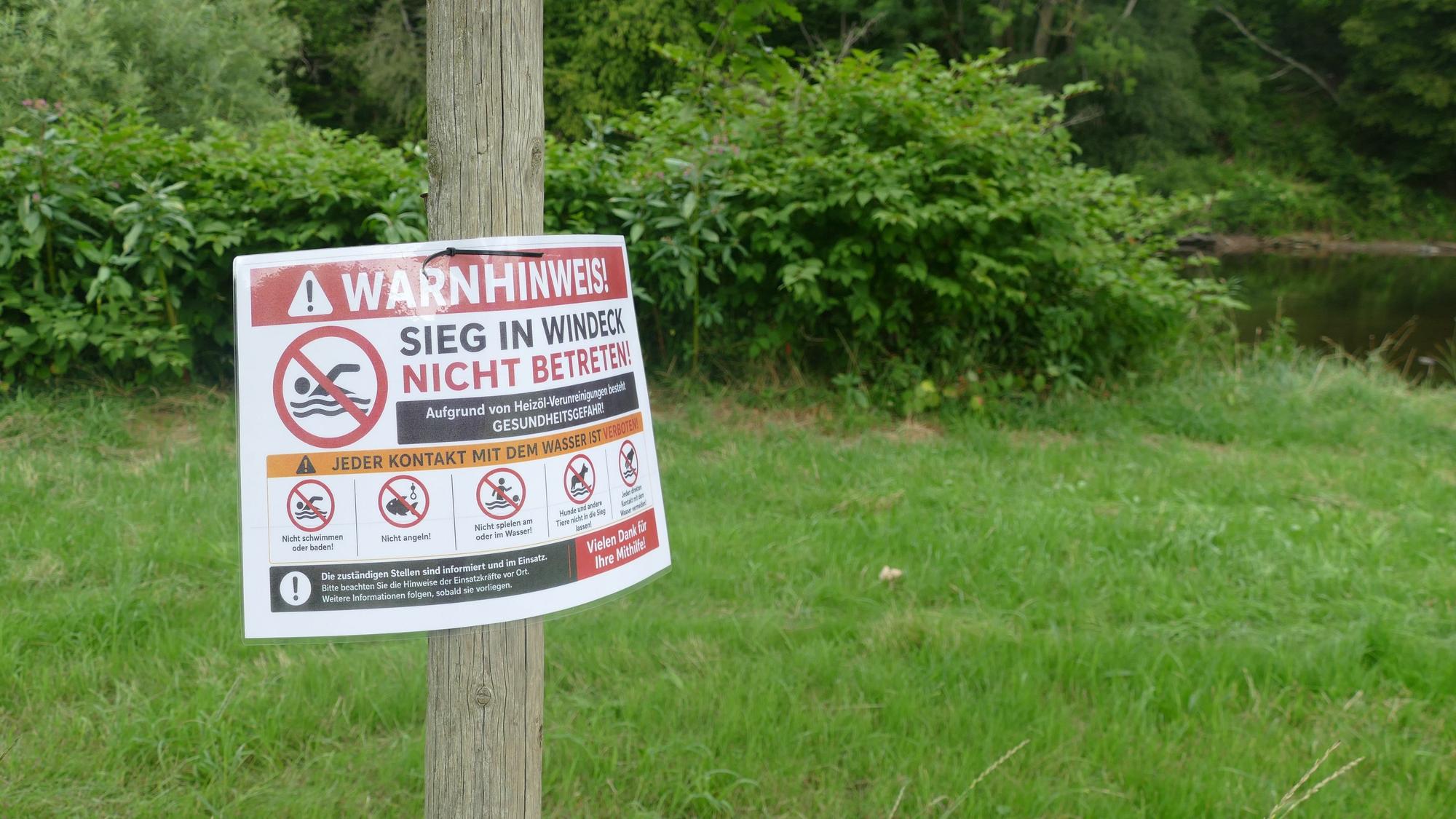Schilder weisen am Siegufer auf das weiter bestehende Badeverbot und die Gefahr für Mensch und Tier hin.