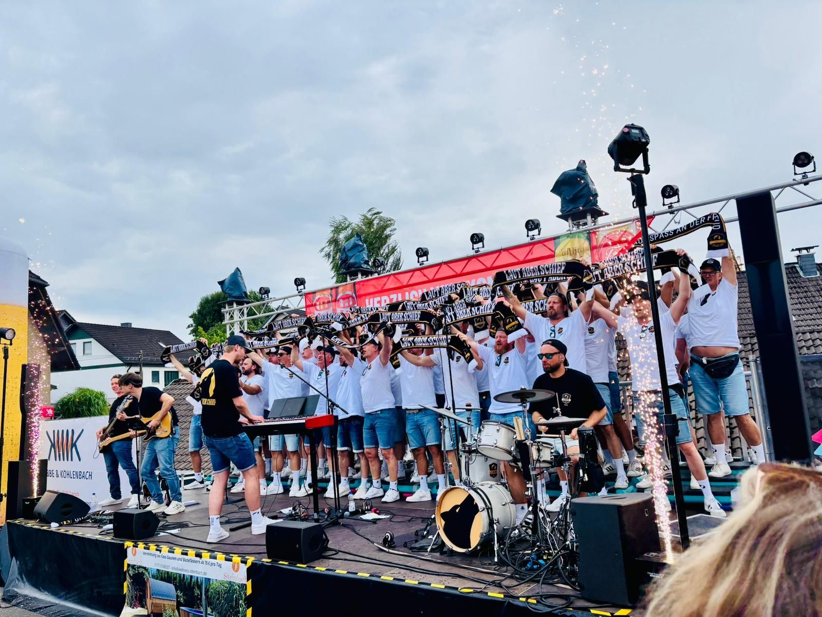 Ein Männerchor steht auf einer Bühne und macht Stimmung.