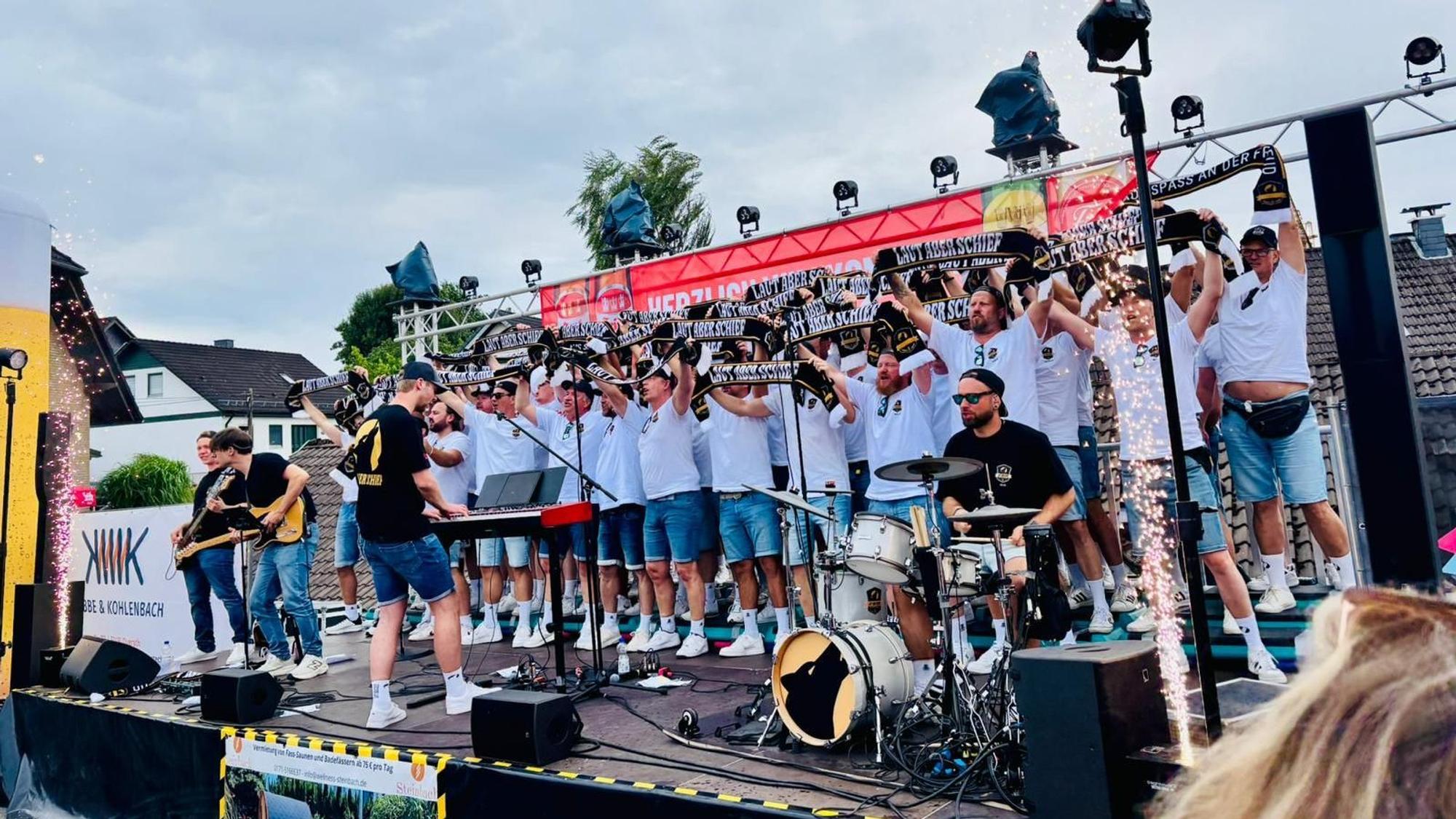 Ein Männerchor steht auf einer Bühne und macht Stimmung.