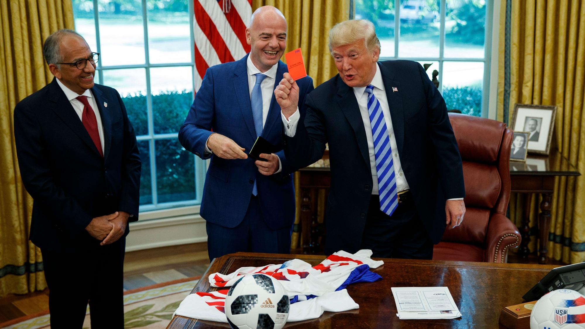 Präsident Donald Trump (r) hält während eines Treffens mit Fifa-Präsident Gianni Infantino (M) und US-Fußballverbandspräsident Carlos Cordeiro im Oval Office des Weißen Hauses eine rote Karte.