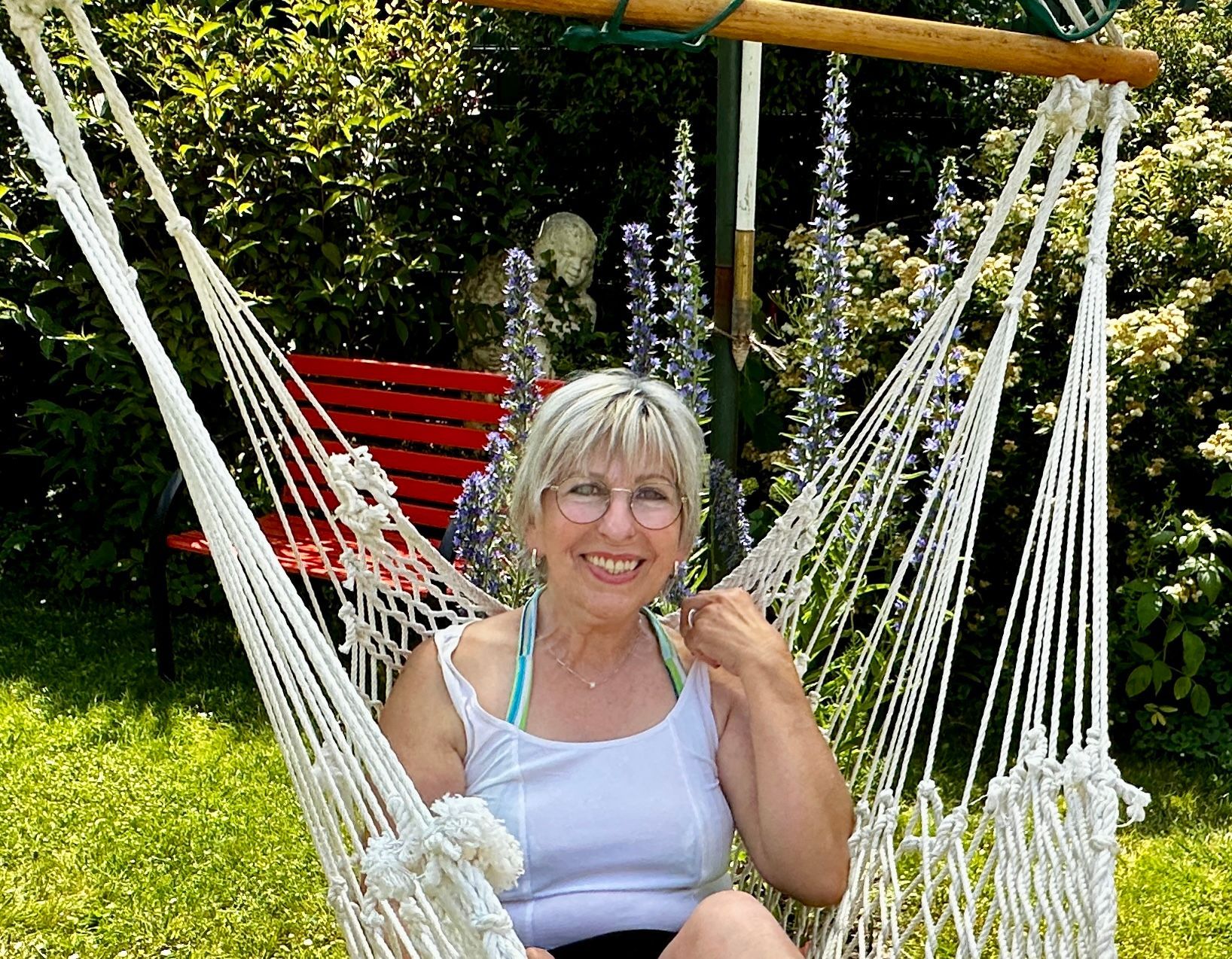 Eine Frau sitzt in einer Hängeschaukel in ihrem Garten.