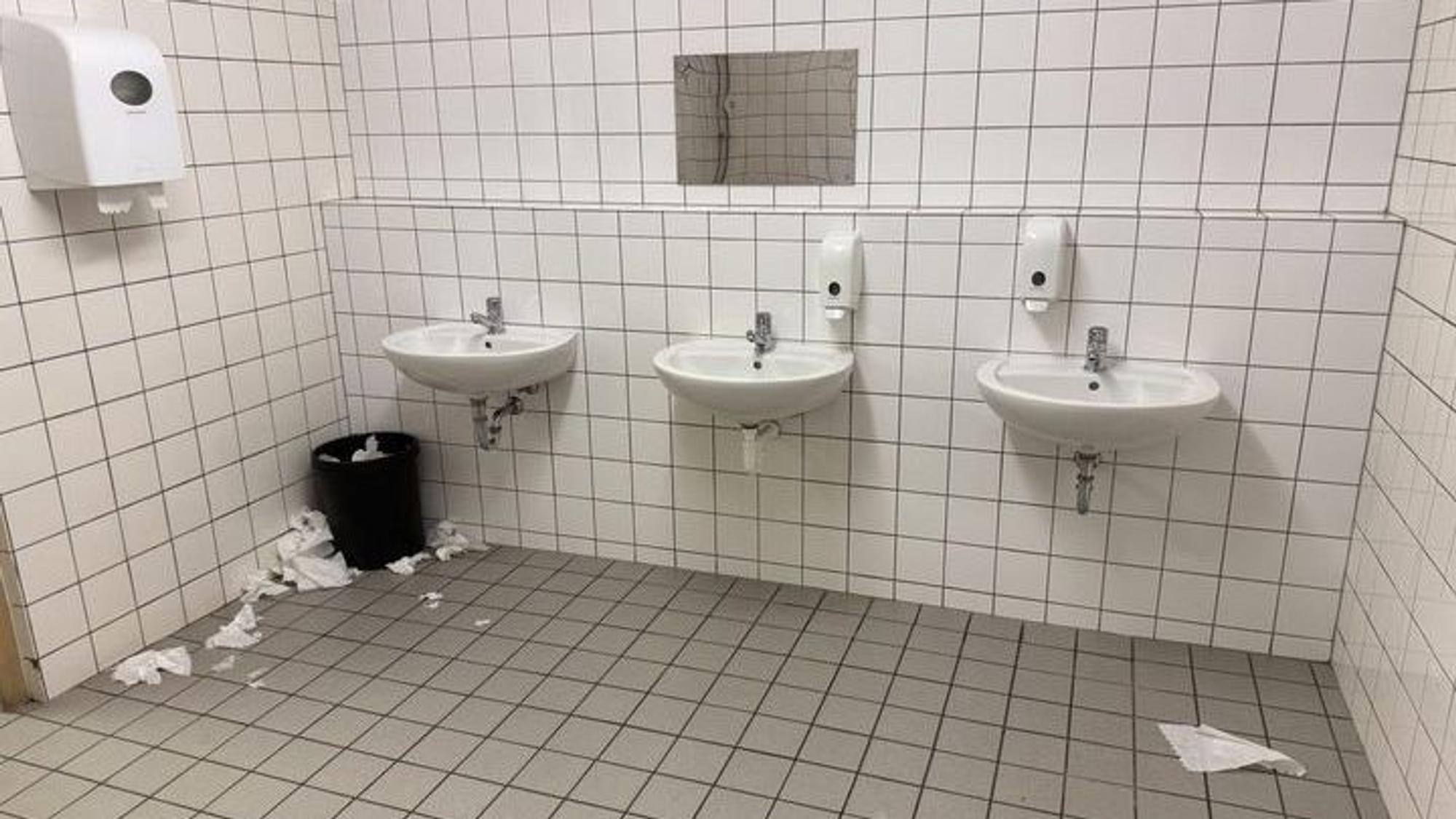 Das Bild zeigt eine Schultoilette. Trockentücher liegen auf dem Boden.