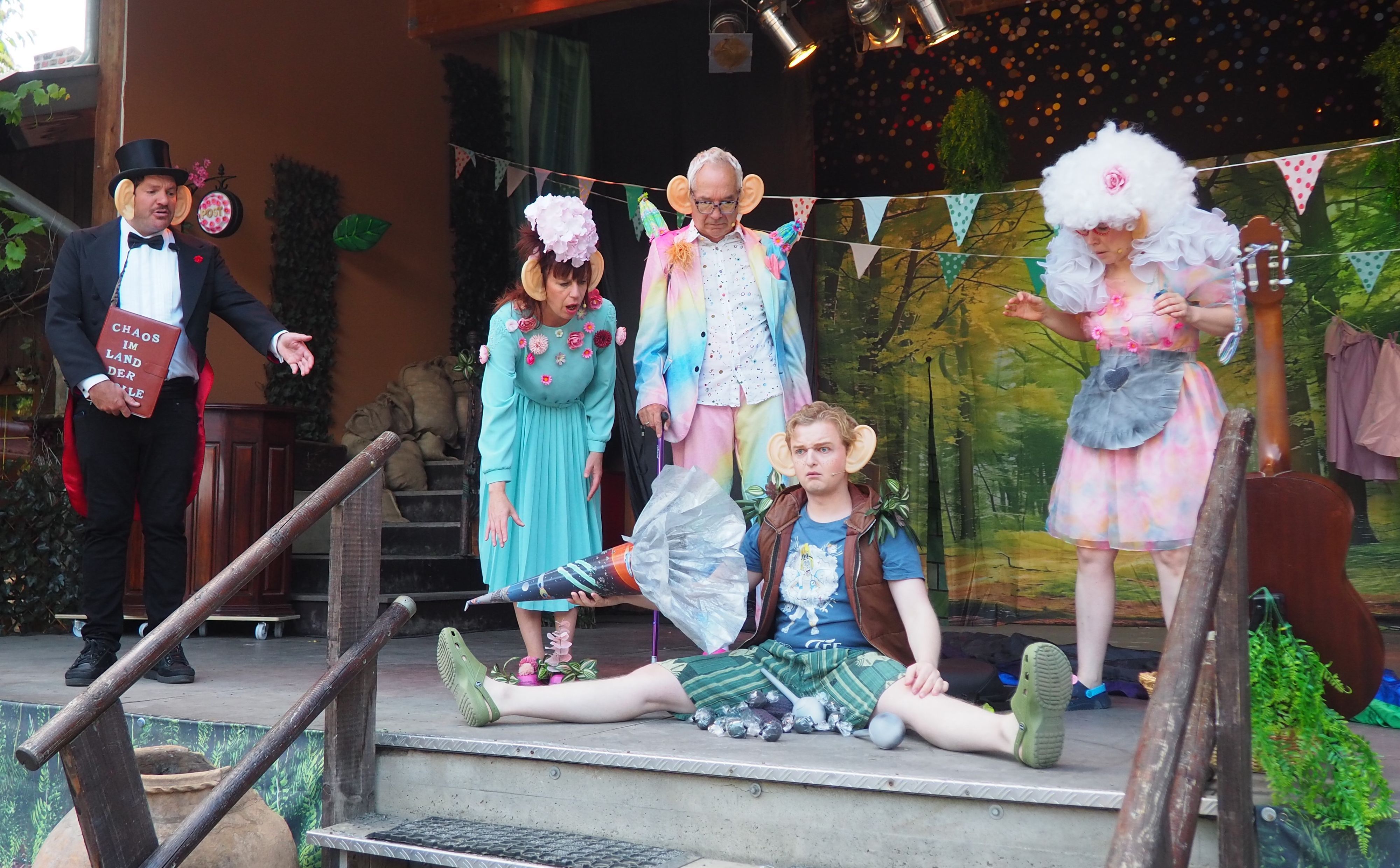 Das Ensemble des Theaters Tintenfass auf der Bühne. Ein Schauspieler sitzt und leert die Schultüte, die anderen schauen entsetzt zu.