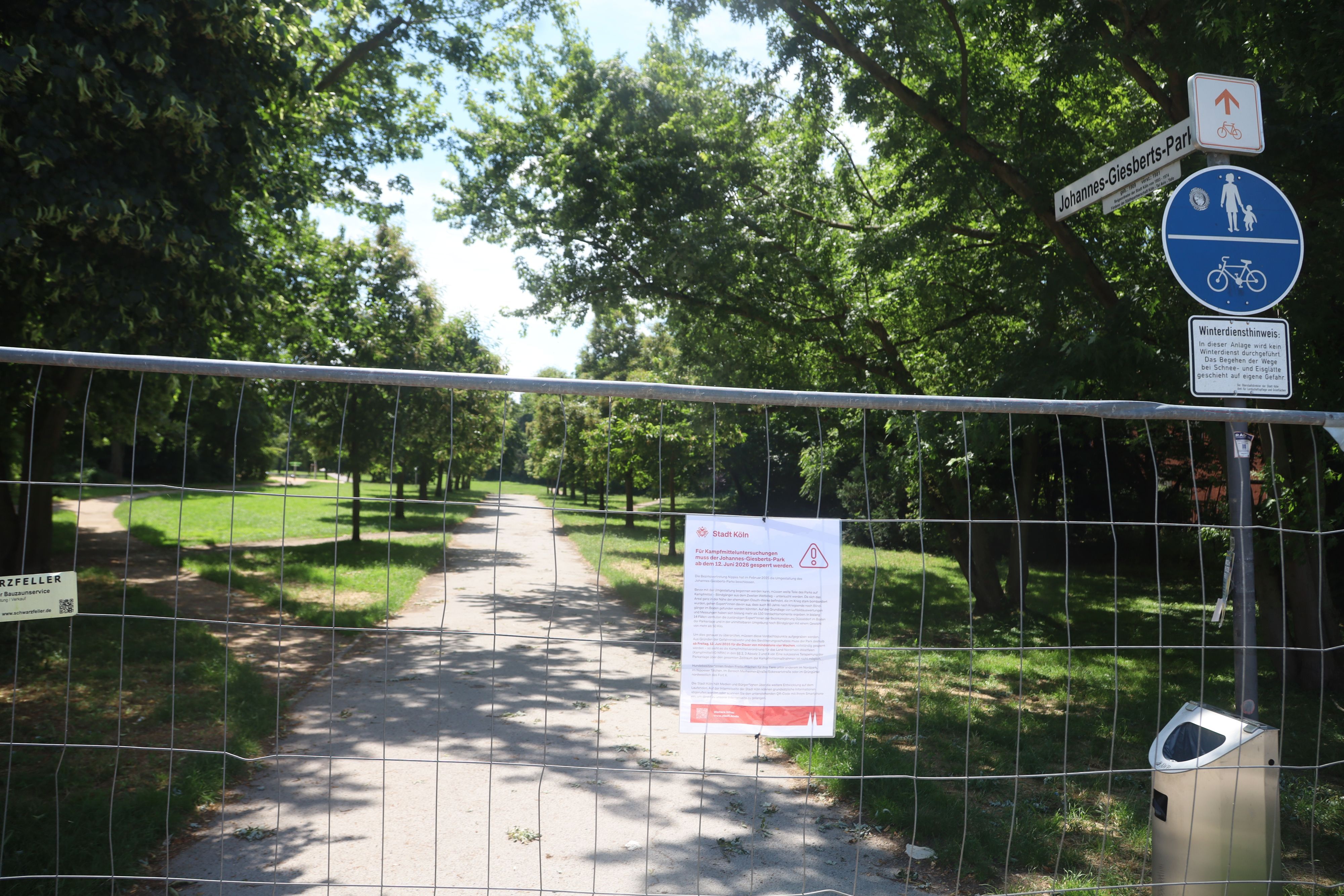 23.06.2026, Köln: Ein Schild der Stadt Köln informiert an einem Bauzaun über die Sperrung des Johannes-Giesberts-Parks für Kampfmitteluntersuchungen. Der Park bleibt während der Arbeiten für Besucher geschlossen. Foto: Arton Krasniqi