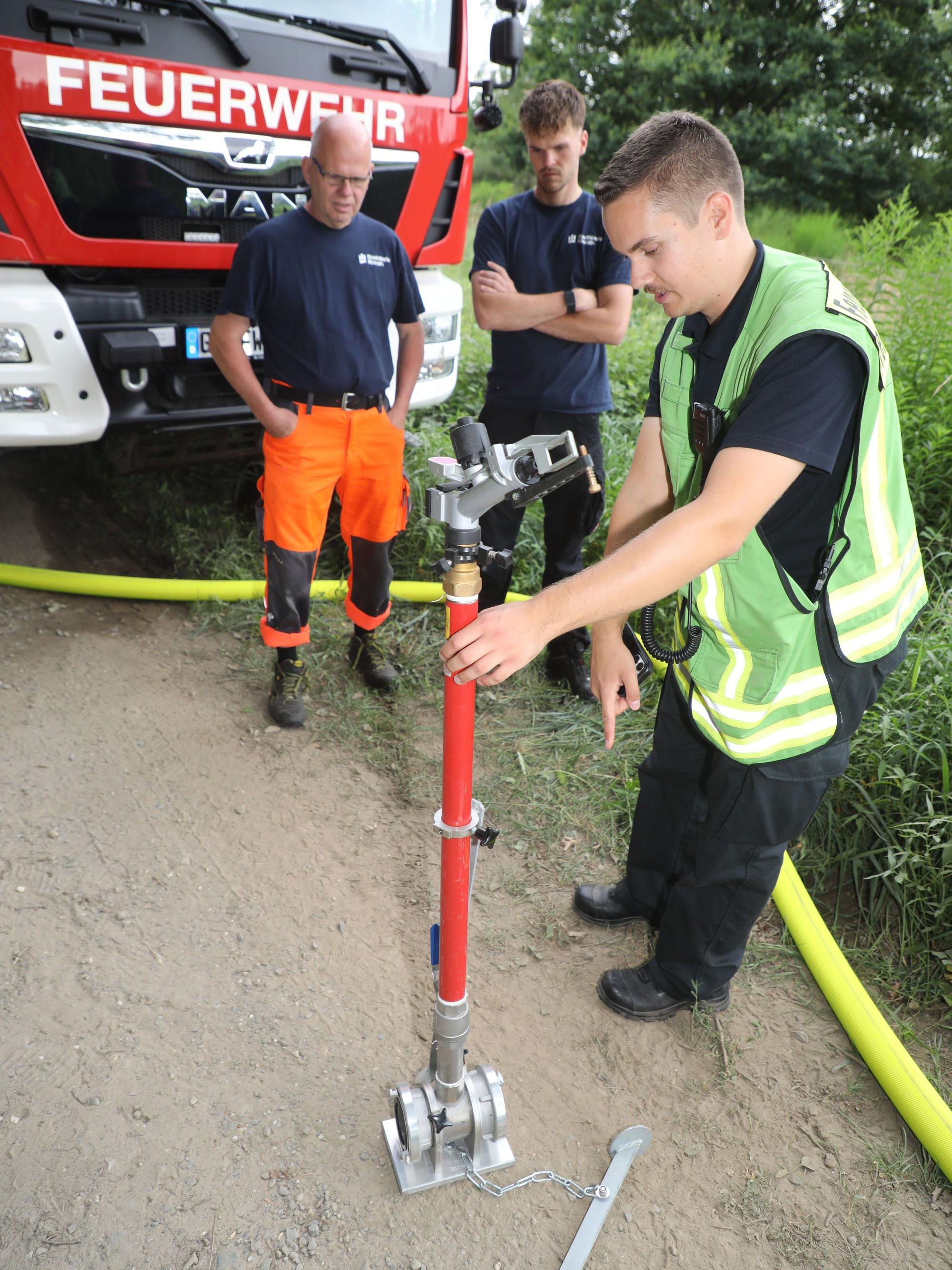 Rösraths Feuerwehrsprecher Luca Meysing zeigt Mitarbeitenden der Stadtwerke Rösrath einen Sprenkler der Kreisregneranlage.