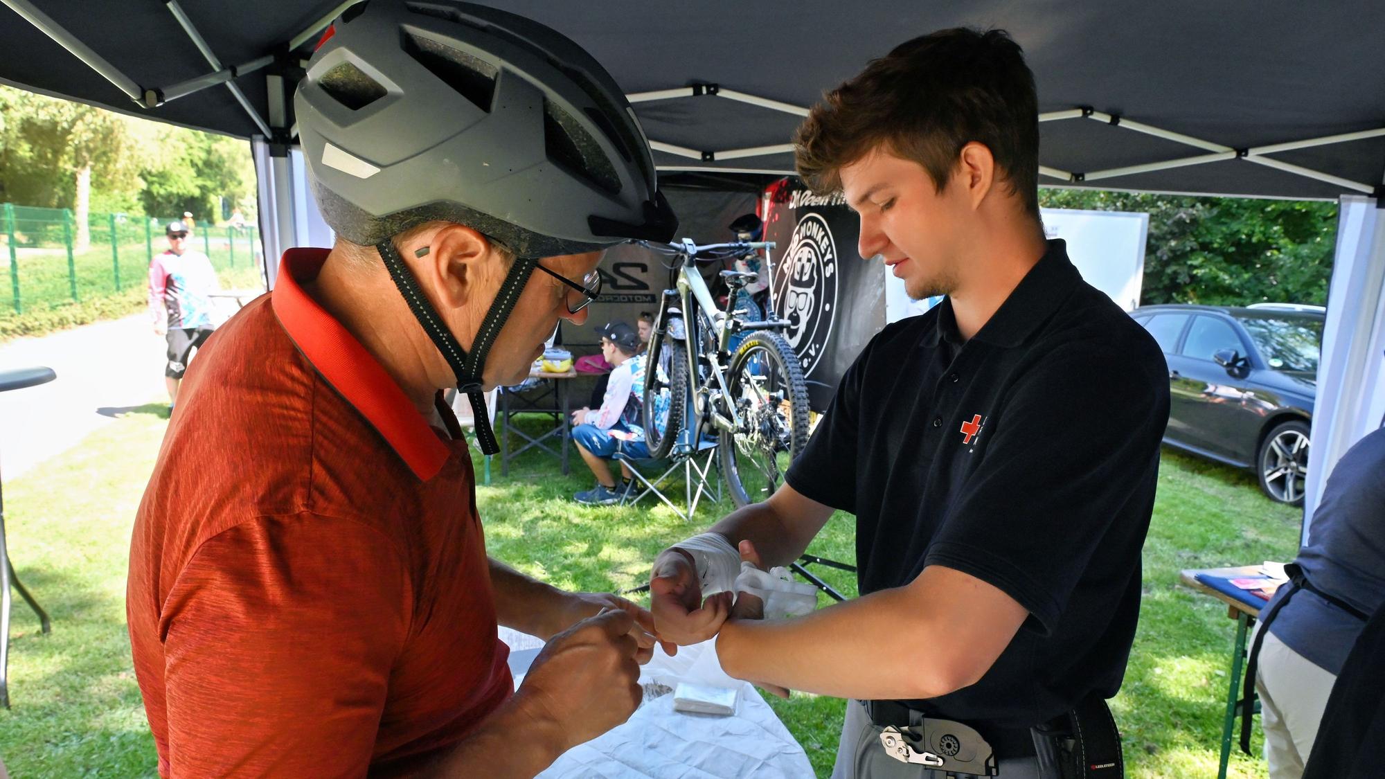 Noah Breidbach wickelt einen Verband um die Hand eines Bikers.