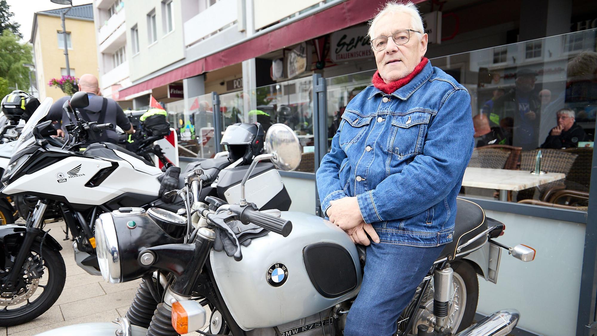 Der grauhaarige Mann sitzt in Jeans-Kluft auf einem BMW-Motorrad.