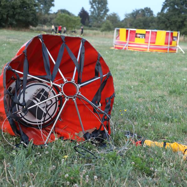 Ein „Bambi Bucket“ für die Brandbekämpfung liegt auf einer Weide, im Hintergrund ist ein Faltbecken der Feuerwehr zu sehen.