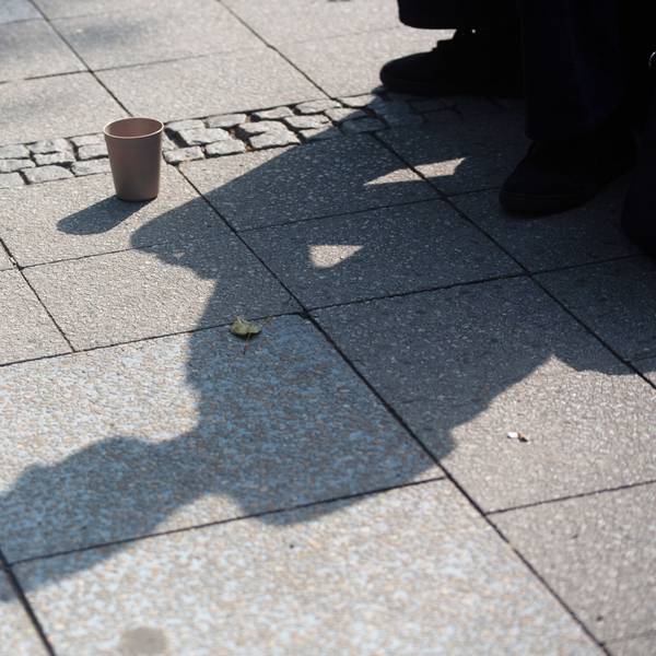 SYMBOLBILD - 10.07.2023, Berlin: Der Schatten einer Person mit einem Becher für Spenden fällt auf den Gehweg. (zu dpa: «Wohnungslosenhilfe fordert Trinkwasserstellen für Obdachlose») Foto: Fernando Gutierrez-Juarez/dpa +++ dpa-Bildfunk +++