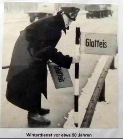 Ein Straßenwärter steckt ein Schild mit der Aufschrift „Glatteis“ in den Schnee am Fahrbahnrand der A4.